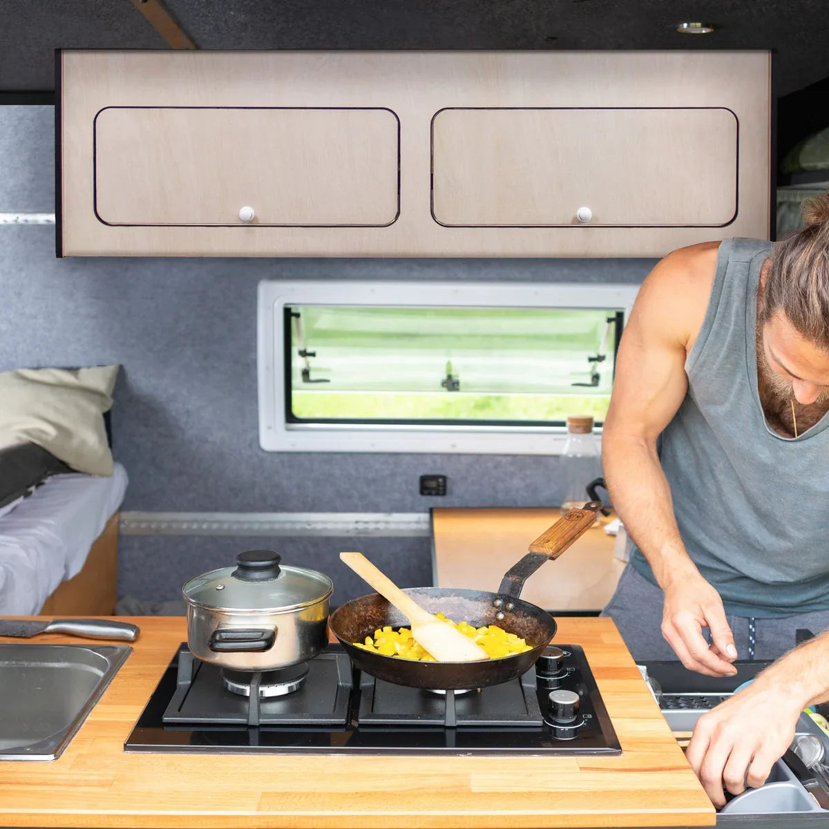 Overhead camper cabinet with black trim, featuring a light wood finish, two drawers, and a modern design in a kitchen setting