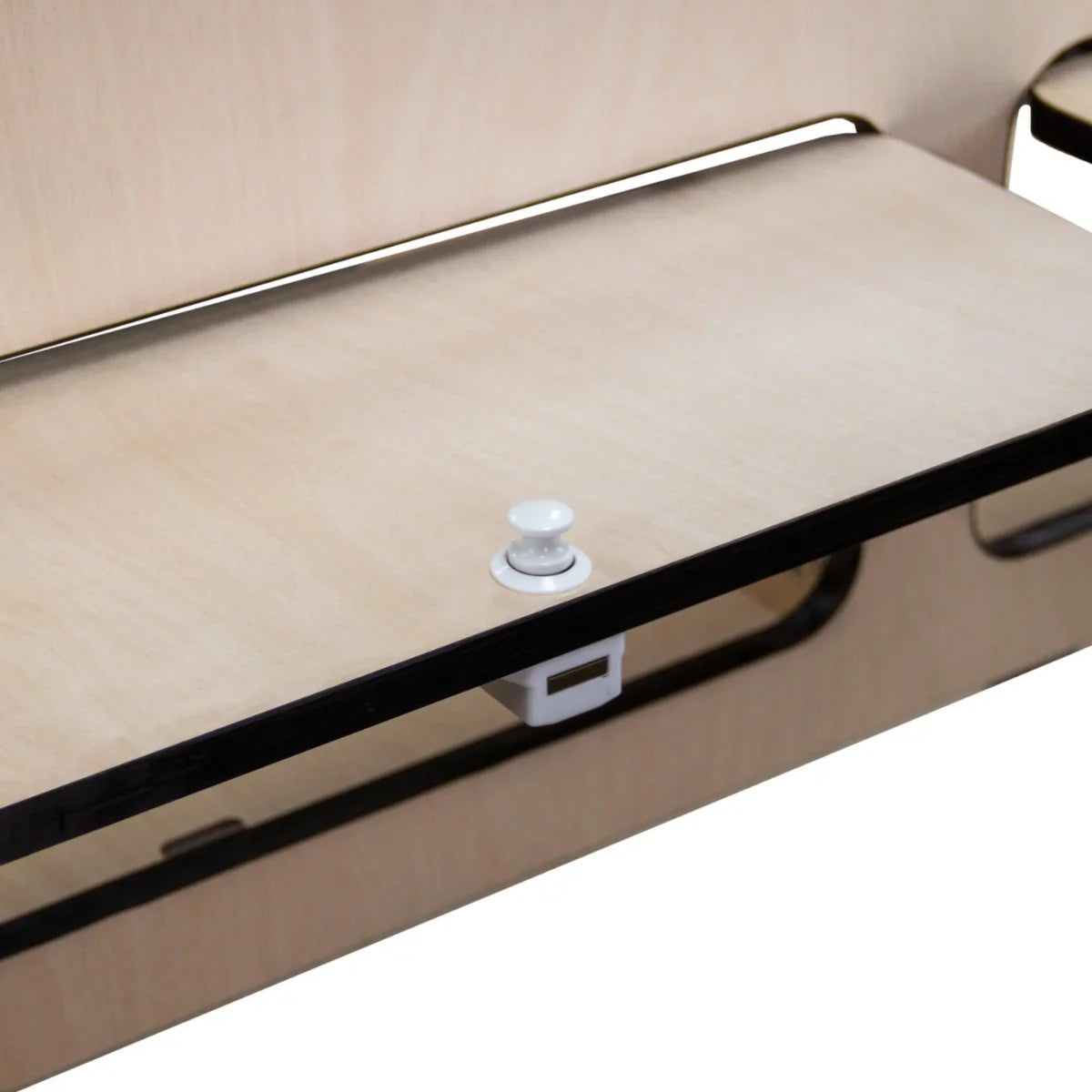 Overhead camper cabinet with black trim, featuring a smooth wooden surface, sleek design, and a white button latch for secure closure