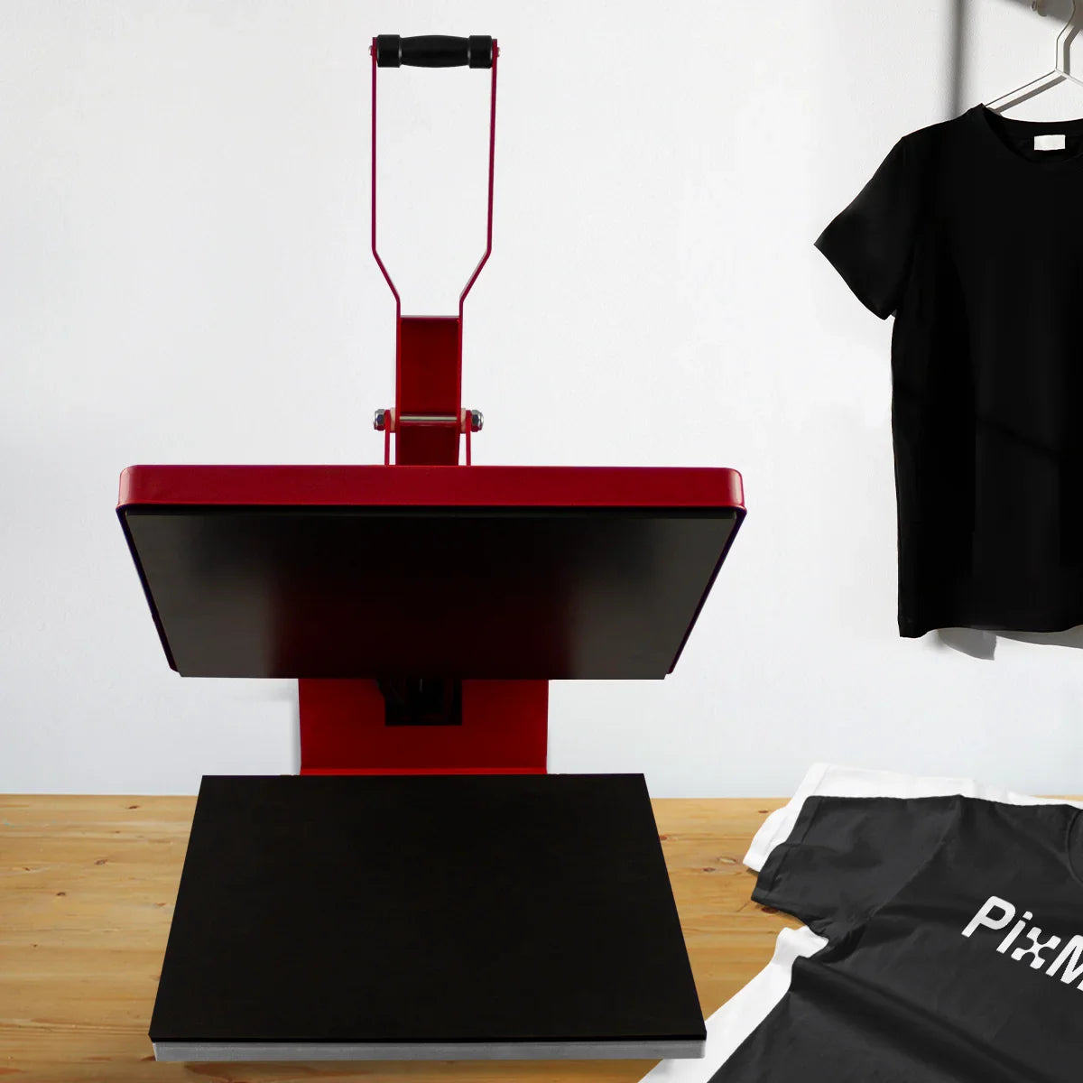 50cm red clam heat press with a black base, positioned on a wooden table next to folded sublimation paper and a gray t-shirt