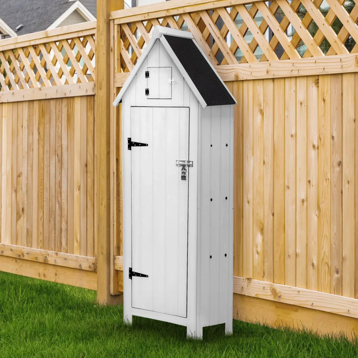 White wooden garden shed with a sloped roof, black shingles, and a lockable door, set against a wooden fence and green grass