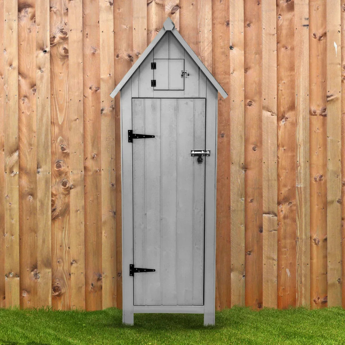 Light grey wooden garden shed with a peaked roof, vertical slats, and black hardware, set against a wooden fence and grass backdrop