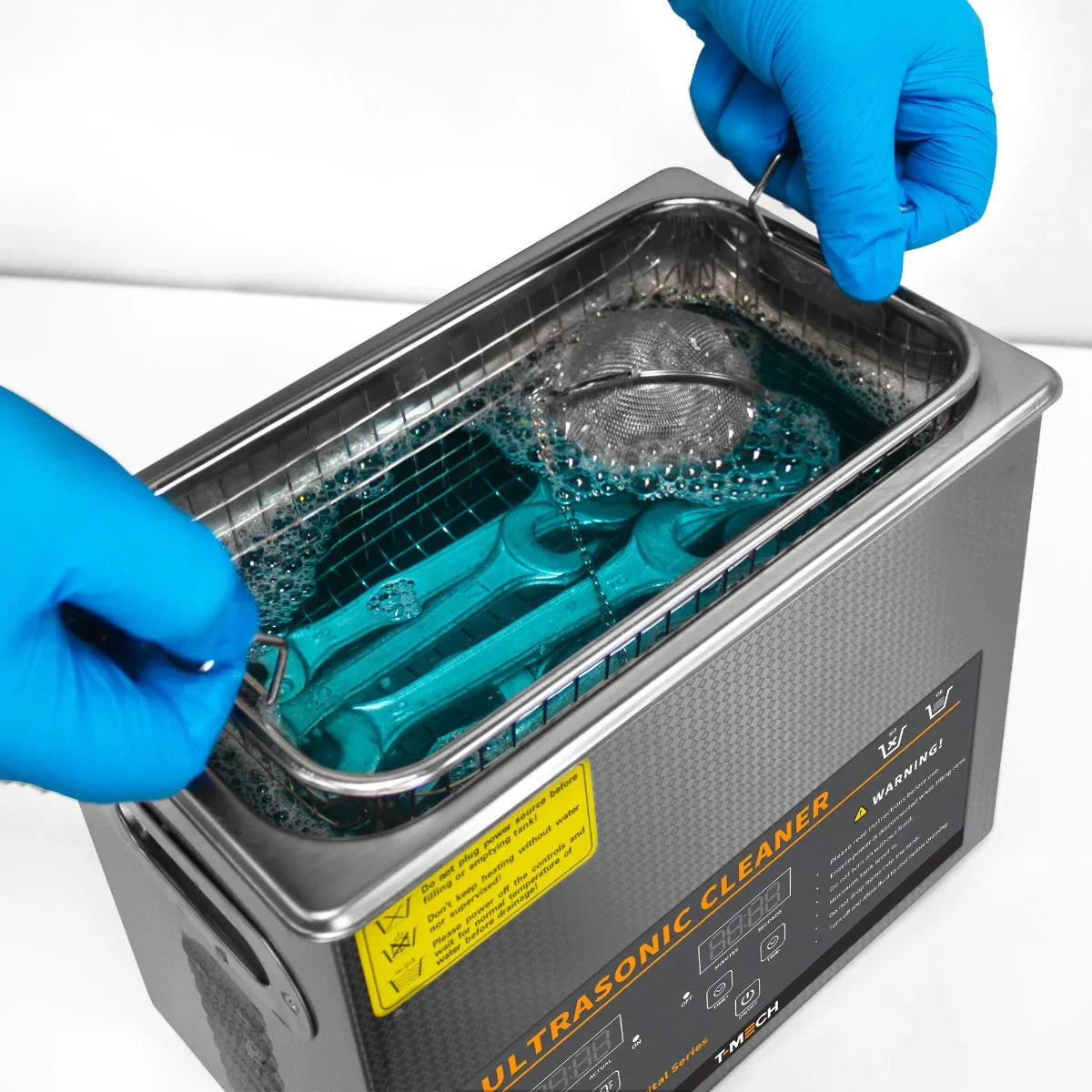T-Mech Ultrasonic Cleaner 3L with blue cleaning solution, stainless steel basket, and hands in blue gloves preparing to use