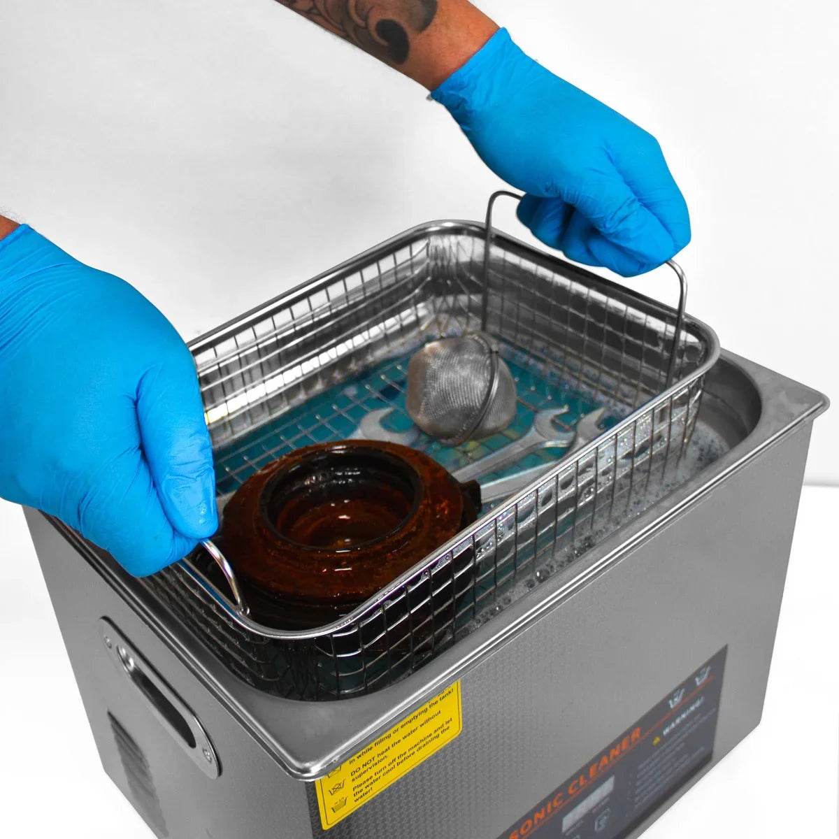 T-Mech Ultrasonic Cleaner 15L with a stainless steel basket, hands in blue gloves lifting a soiled part from the cleaning solution