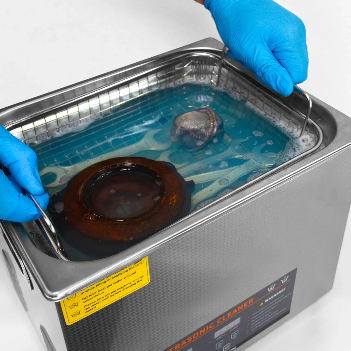 T-Mech Ultrasonic Cleaner 30L with blue cleaning solution, metal basket, and hands in blue gloves holding the unit's handles