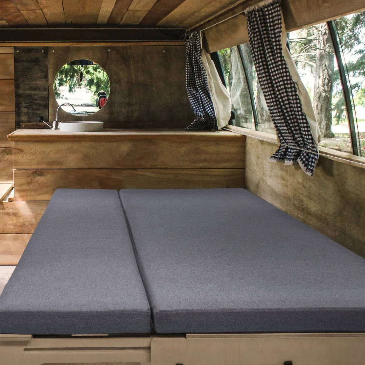 Cozy gray Camper Van Bed with a smooth texture, set in a wooden interior featuring checkered curtains and a circular window