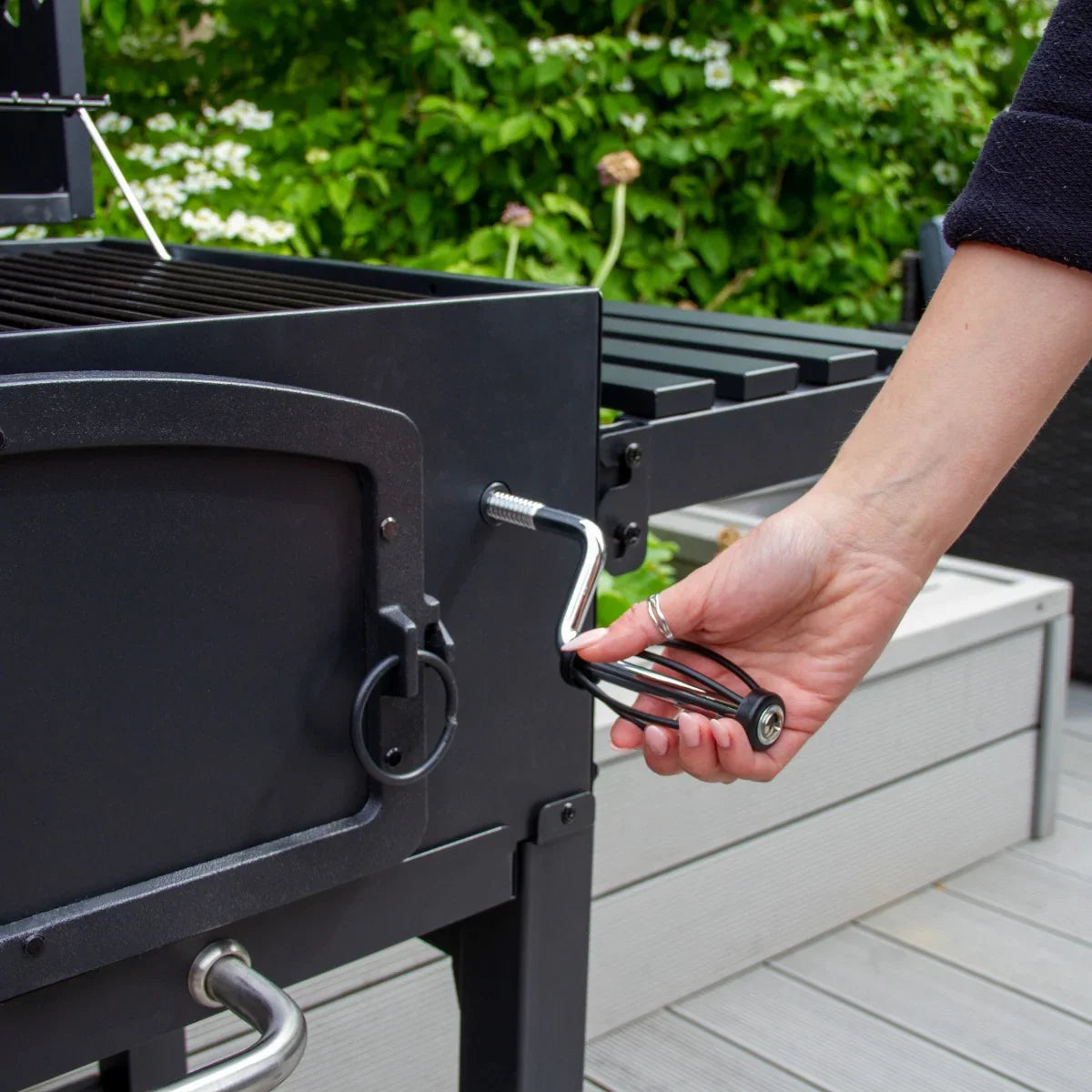 XL BBQ smoker grill with a hand adjusting the temperature control, featuring a sleek black finish and sturdy construction