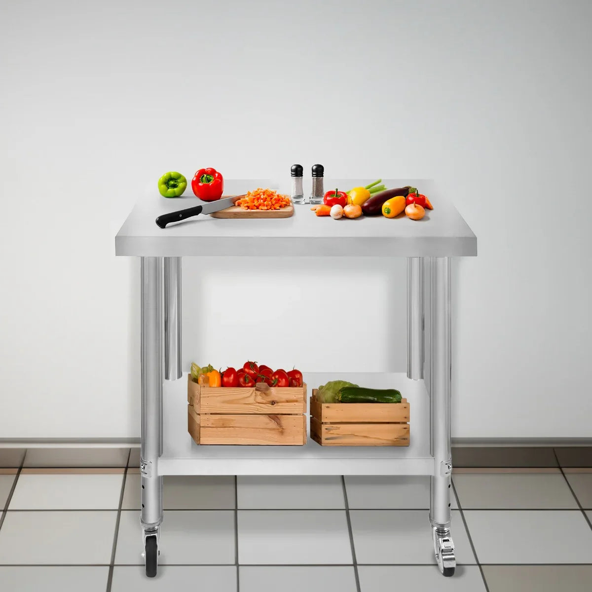 Stainless steel KuKoo work table with a chopping board, fresh vegetables, and wooden crates on a tiled floor, ideal for food prep