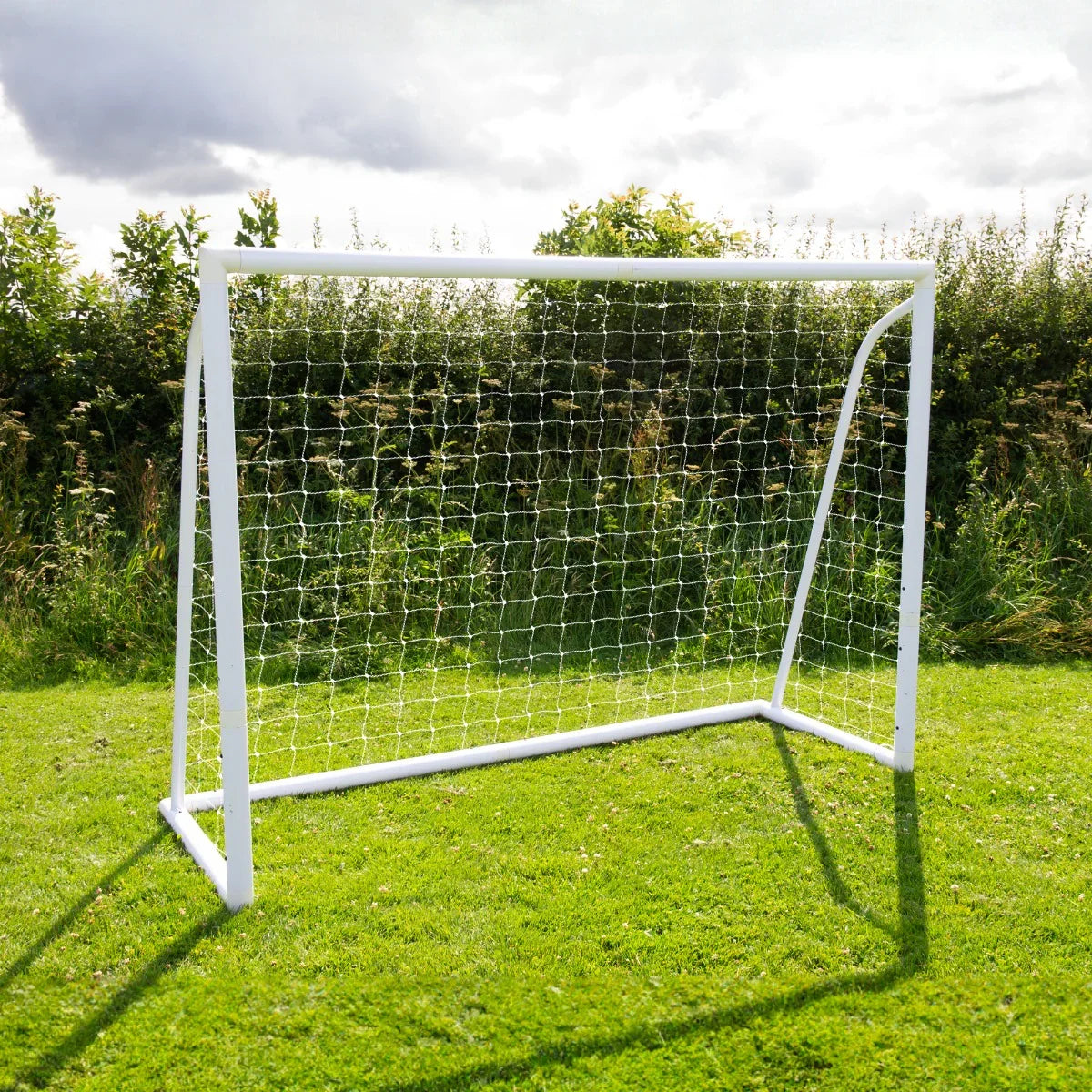 8 x 6ft white football goal with a sturdy net, set on green grass under a cloudy sky, ideal for backyard games and training