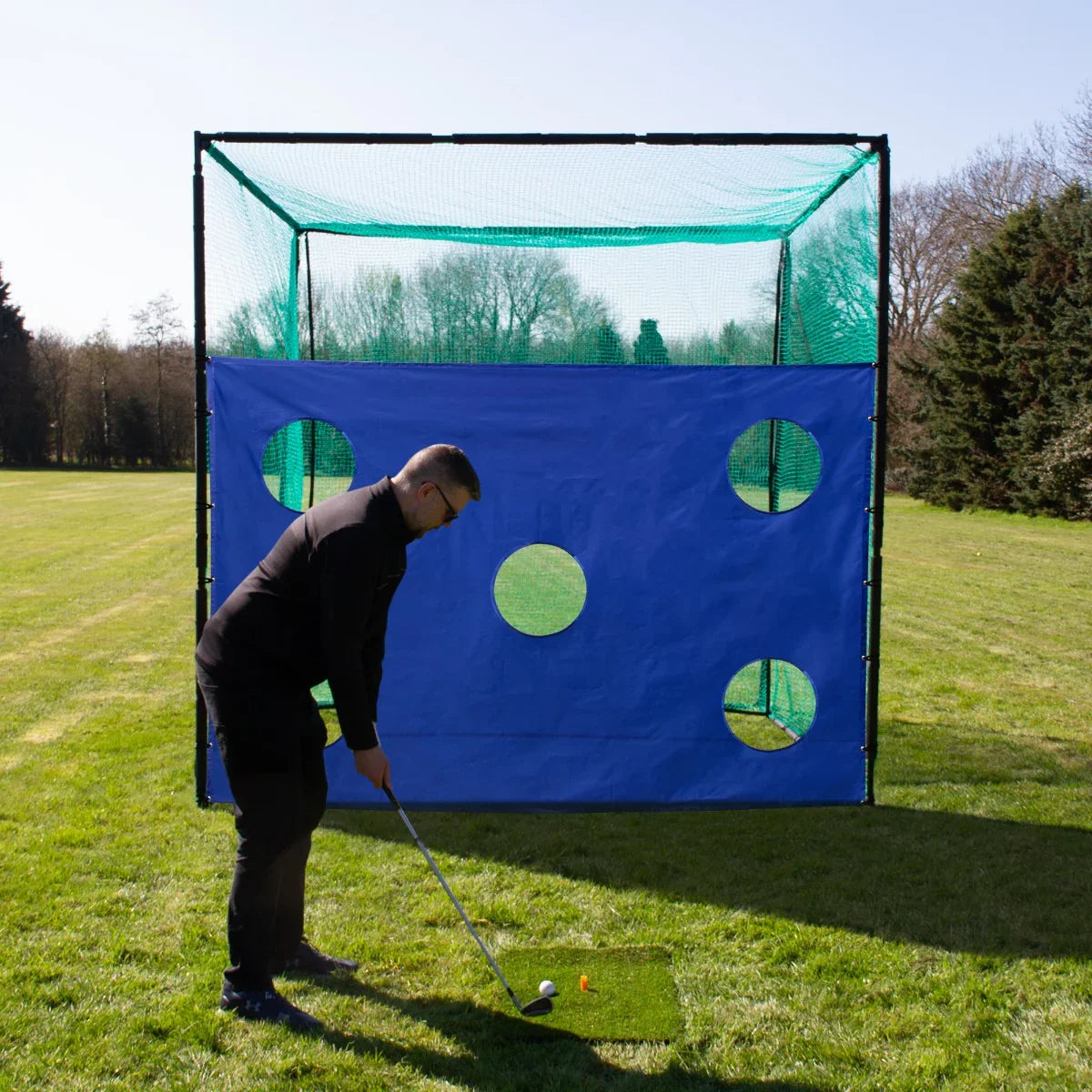 Golf cage target sheet in vibrant blue with circular holes, set on a grassy field, featuring a golfer preparing to swing