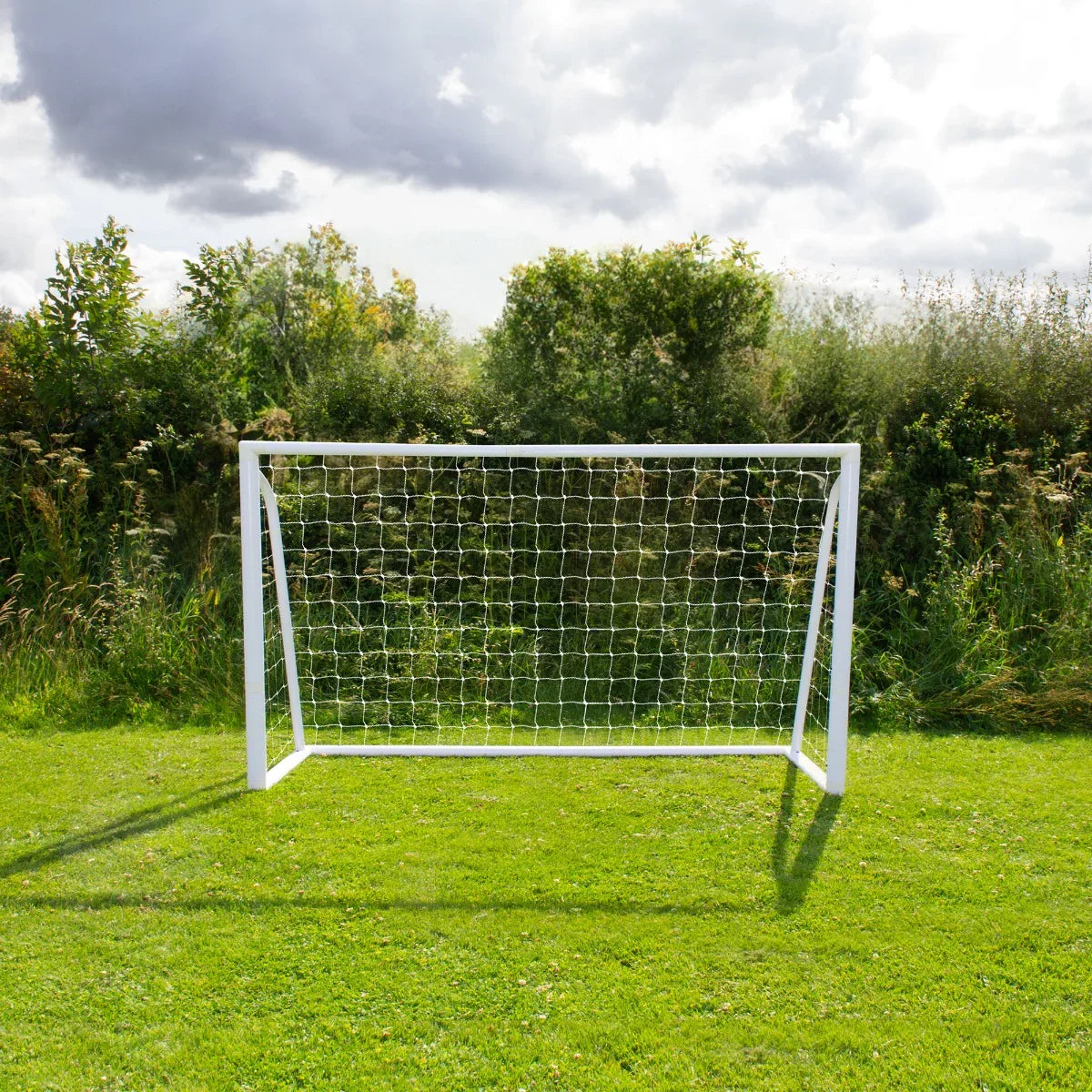 6 x 4ft football goal with a sturdy white frame and netting, set against a lush green field and cloudy sky backdrop