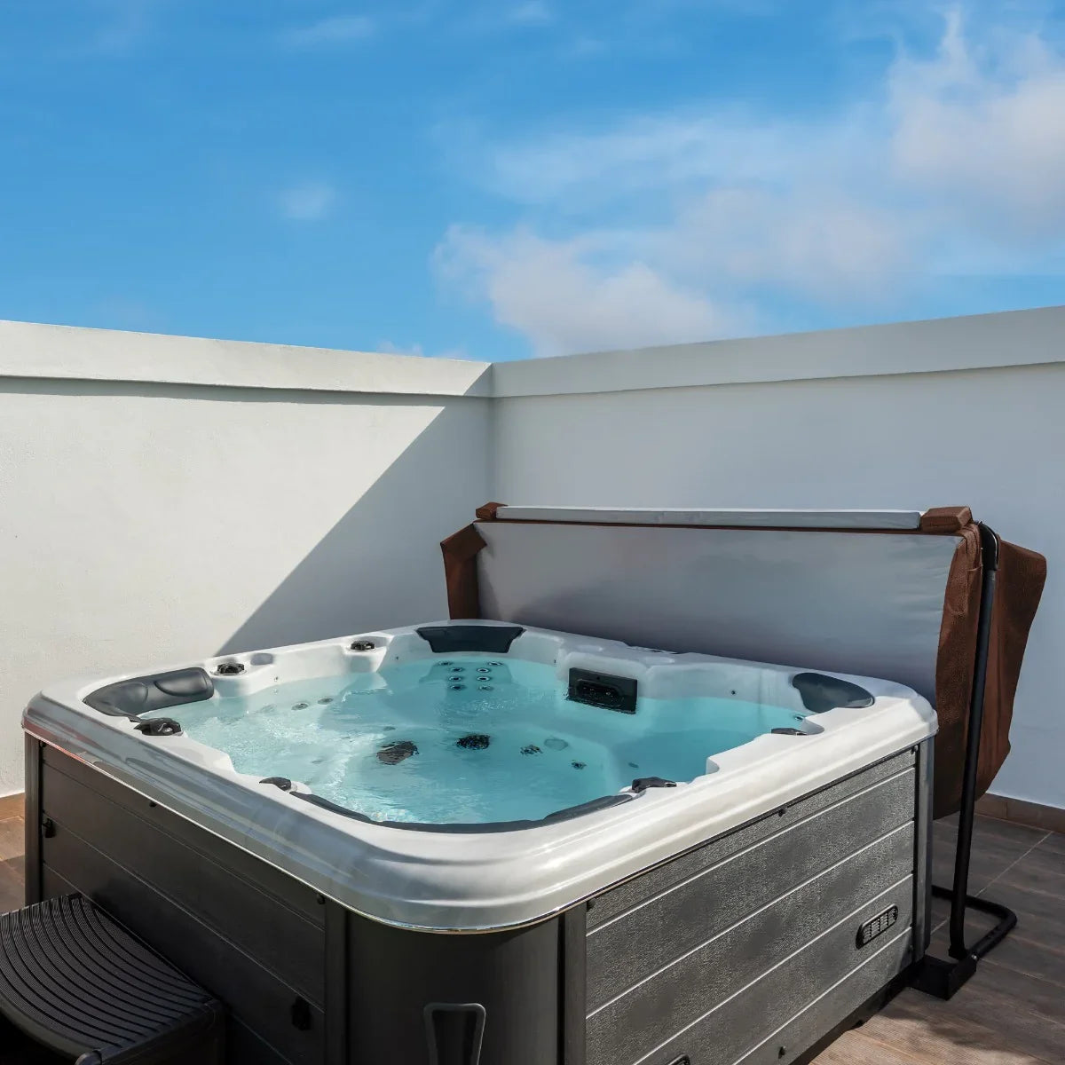 Brown 2.2m hot tub spa cover partially open, revealing a bubbling water surface and sleek black exterior under a clear blue sky