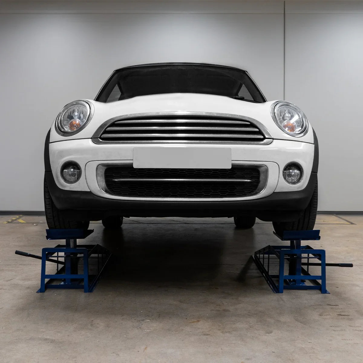 Hydraulic car ramps supporting a silver vehicle, showcasing sturdy blue metal construction and a stable design for safe lifting