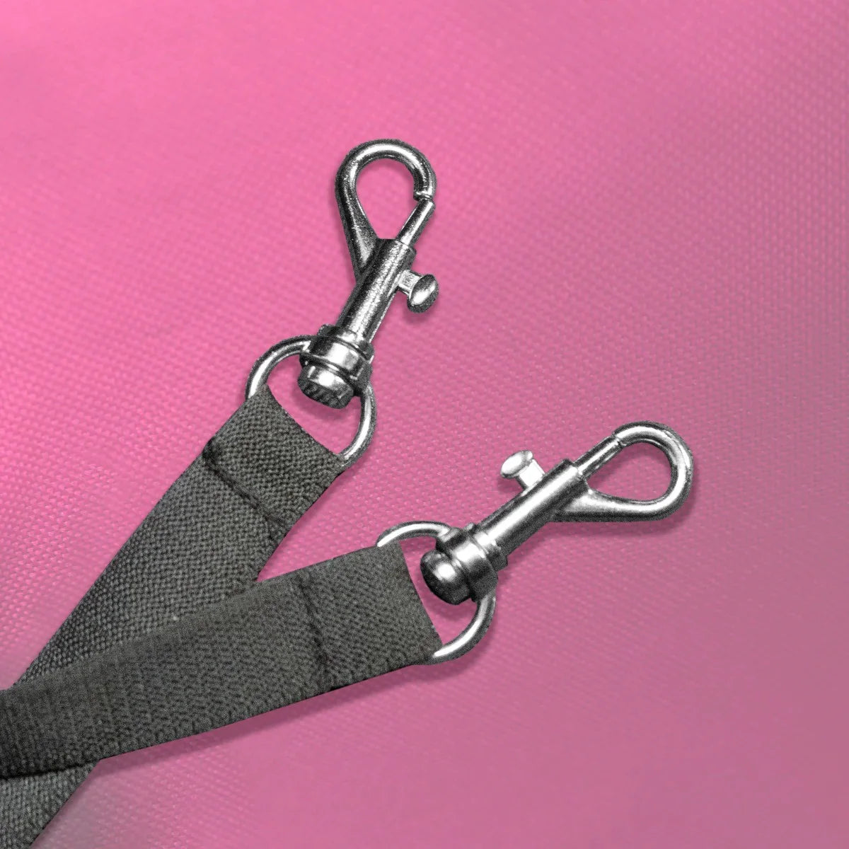 Close-up of sturdy metal clips on a black strap, designed for securing pets in a pink pet stroller with rain cover