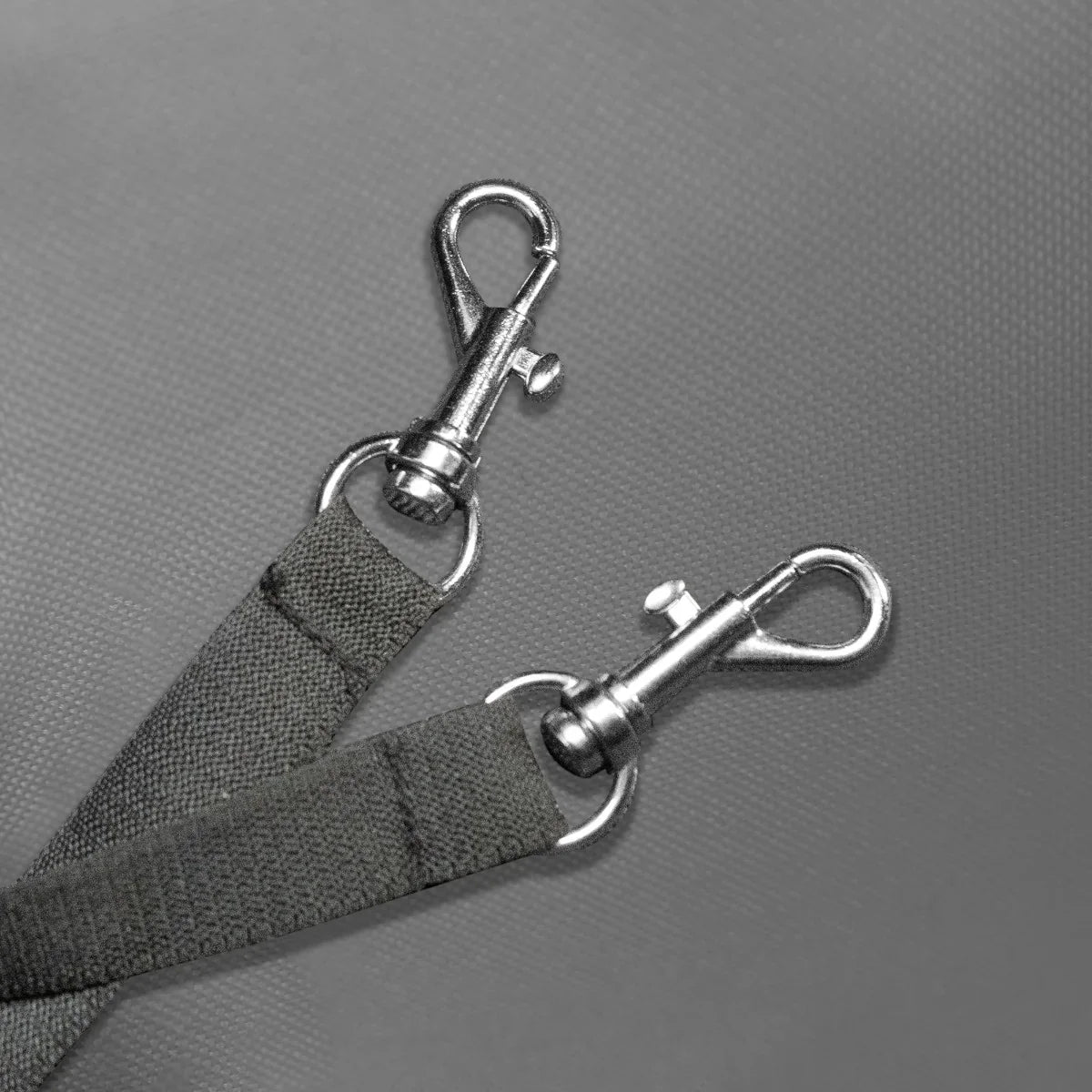 Close-up of durable grey fabric straps with metal clips, designed for securing pets in a grey pet stroller with rain cover