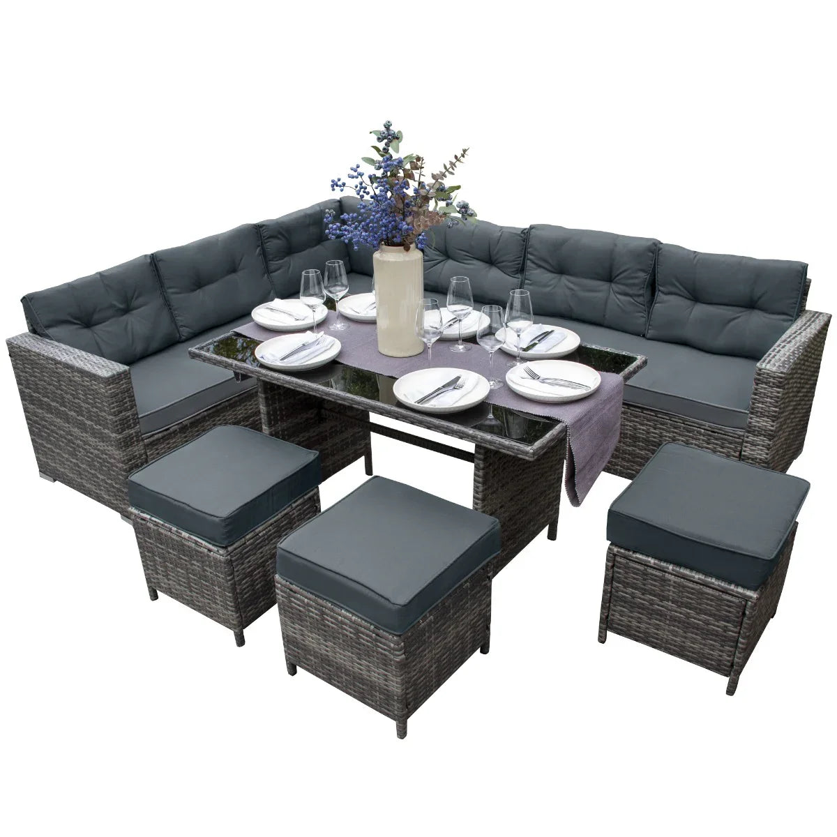 Grey rattan corner set featuring plush cushions, a glass-topped table, and matching ottomans, perfect for outdoor gatherings