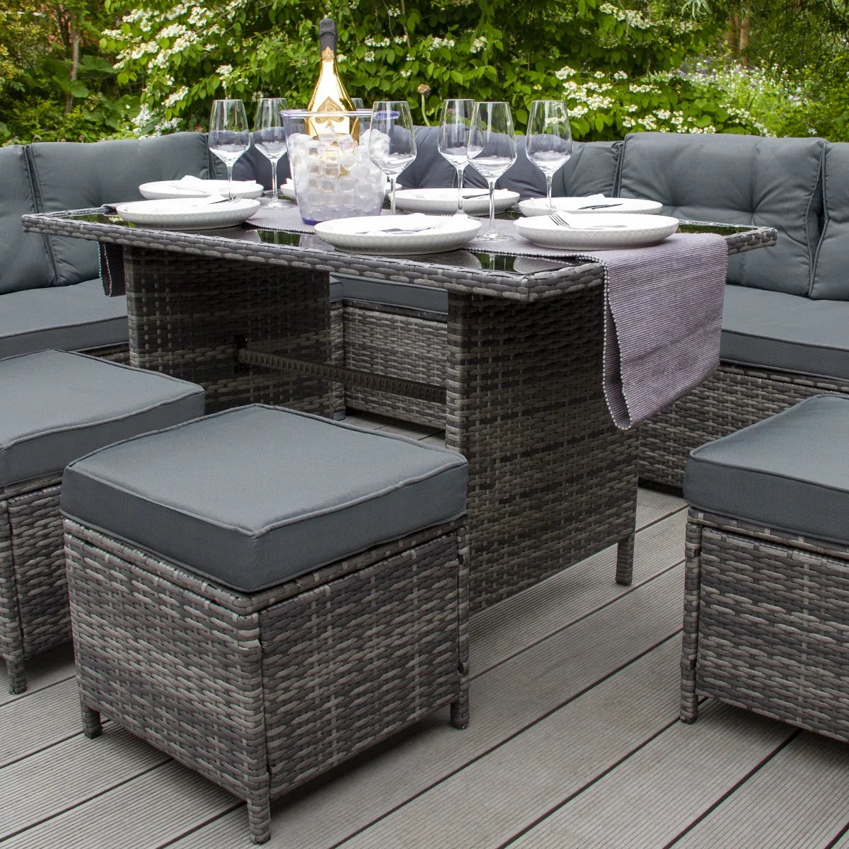 Stylish grey rattan corner set with plush cushions, glass-top table, and elegant dining setup, perfect for outdoor gatherings