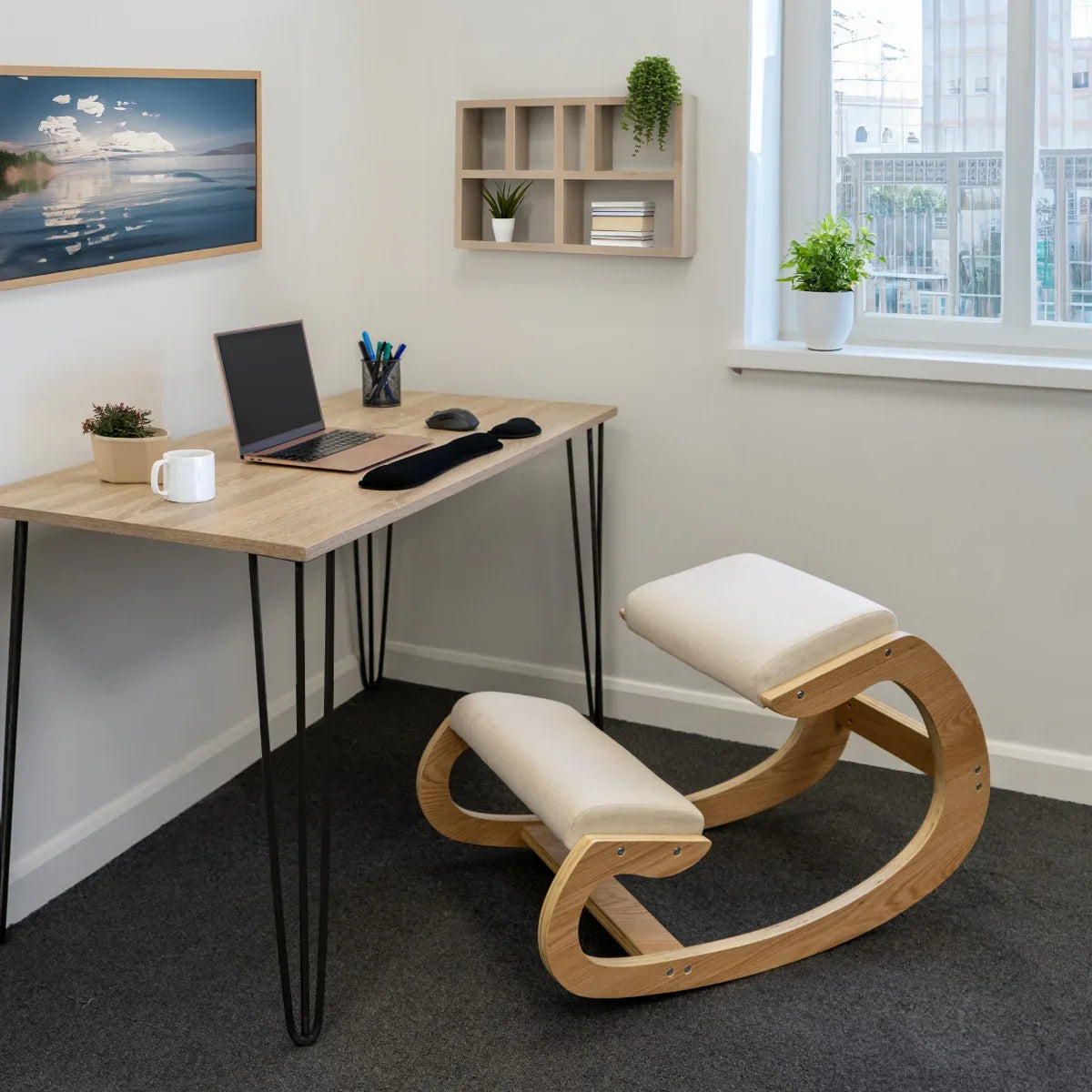 Ergonomic kneeling chair with a natural wood frame and soft cream cushions, placed beside a modern desk in a bright office setting