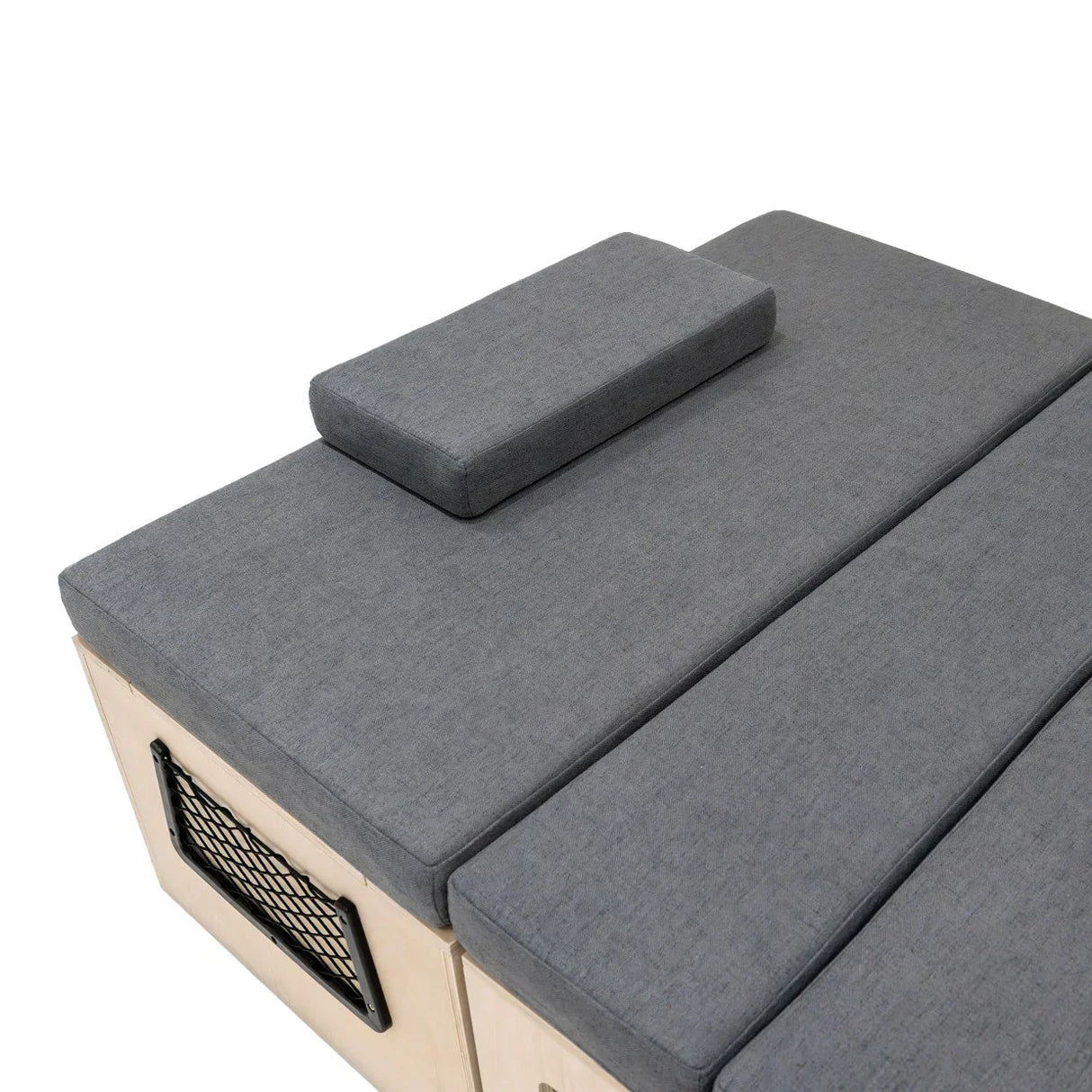 L-shaped camper van bed with soft gray upholstery, featuring a removable back cushion and a sturdy wooden base for comfort and support