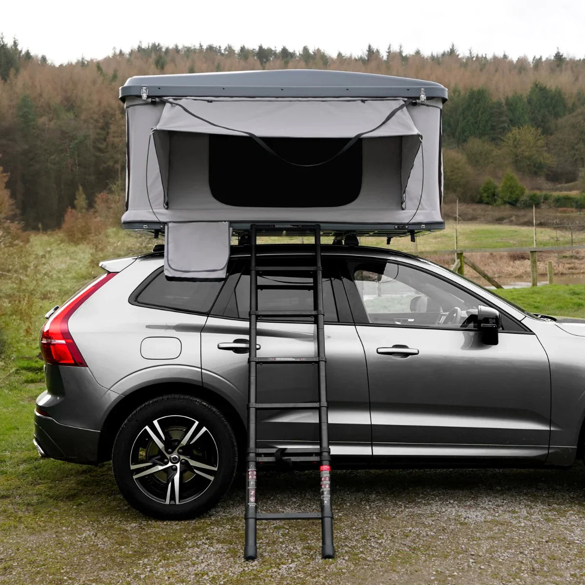 Grey car roof tent mounted on a vehicle, featuring a sturdy ladder, spacious interior, and a weather-resistant design in a natural setting