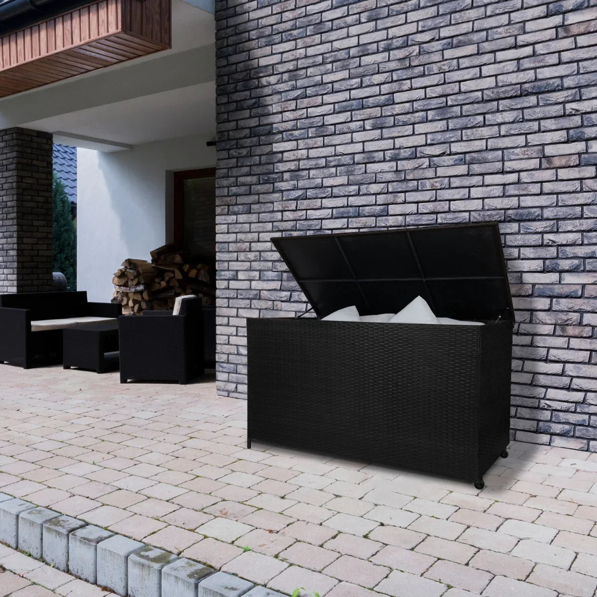 Black rattan storage box with a spacious 582L capacity, featuring a hinged lid and textured weave, placed on a patio with stone flooring