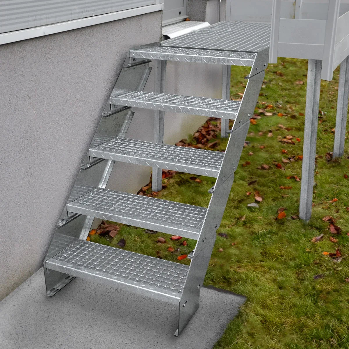 Adjustable 3 section galvanised staircase with six textured steps, 900mm wide, leading from a concrete surface to grass