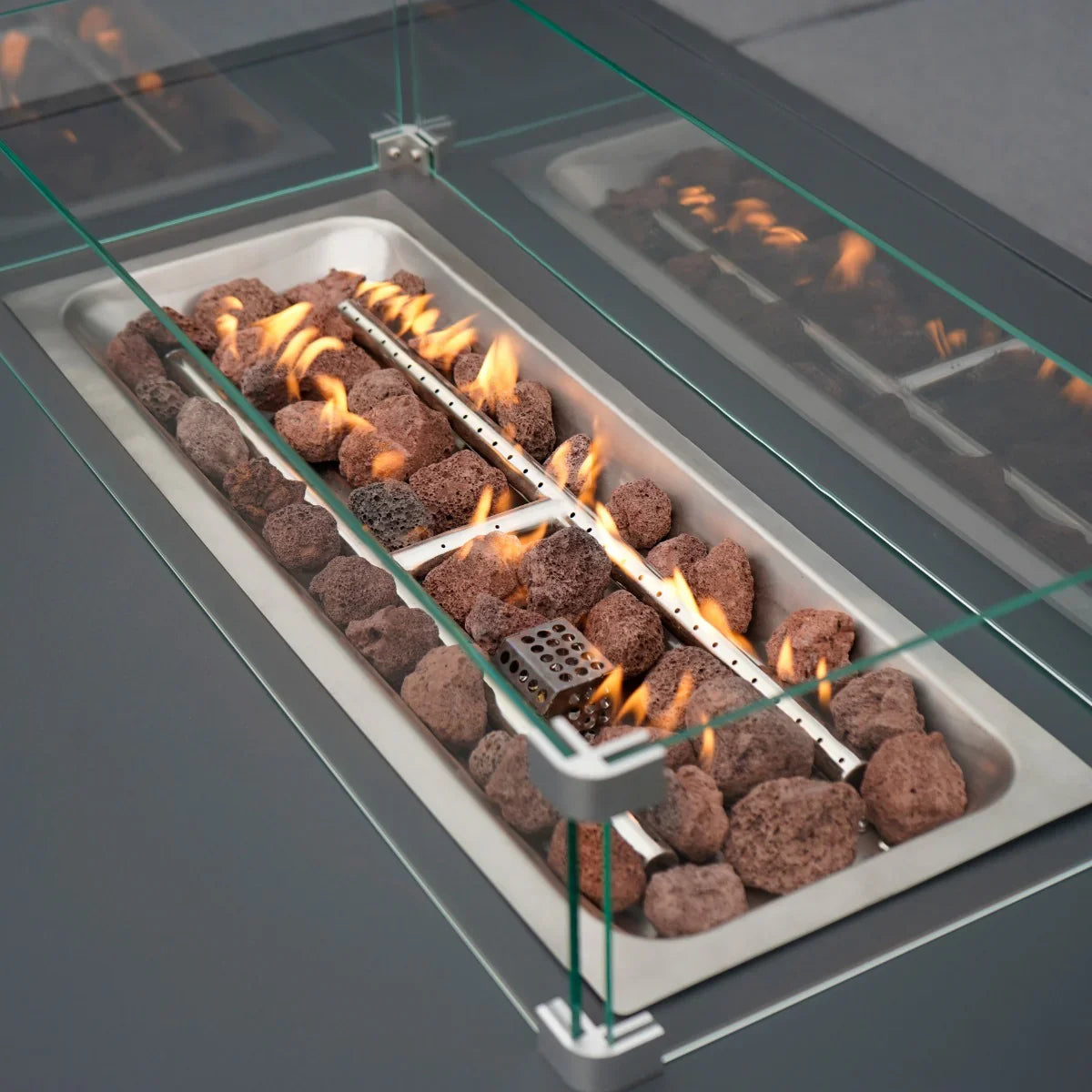 Modular garden furniture set featuring an anthracite grey fire pit with glass surround, showcasing vibrant flames and decorative stones