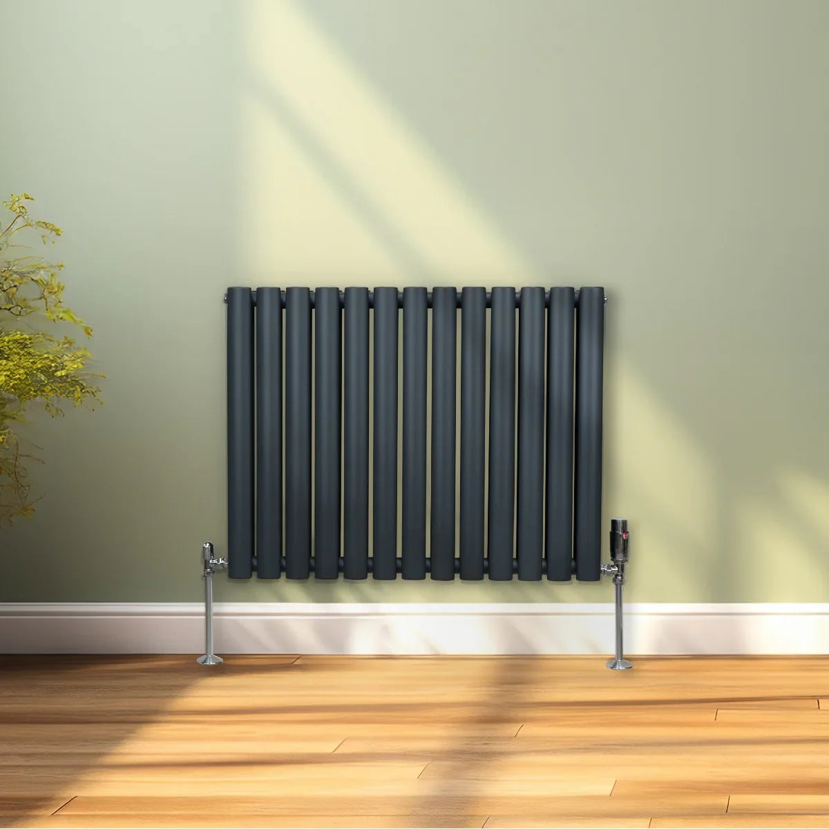 Oval column radiator in anthracite grey, featuring sleek vertical bars and a modern design, mounted on a light green wall