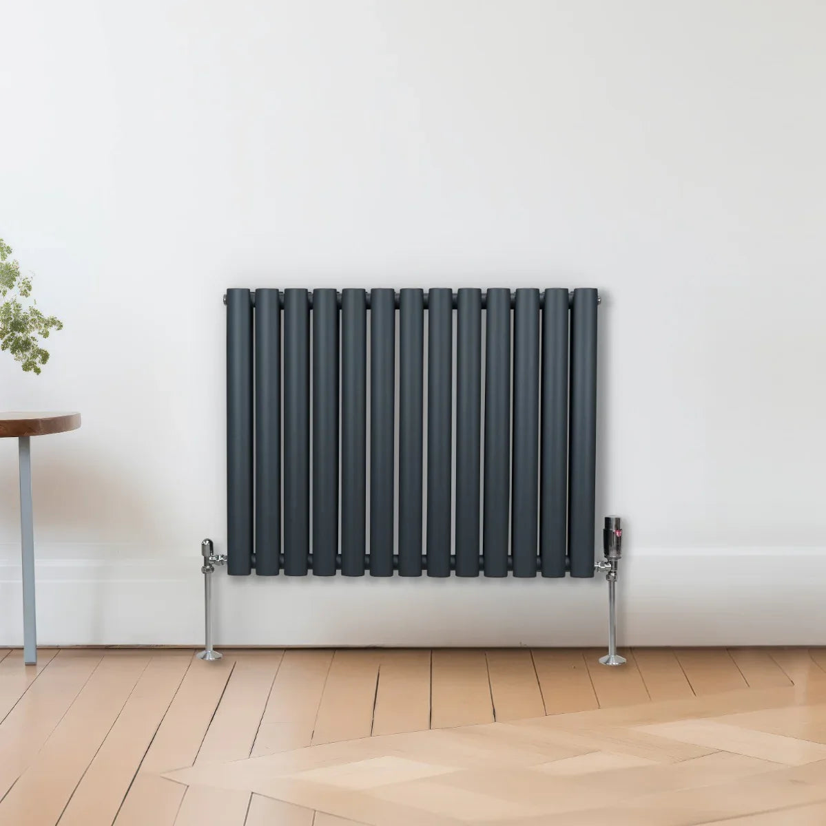 Oval column radiator in anthracite grey, 600mm x 780mm, featuring vertical tubes and sleek design, mounted on a wooden floor