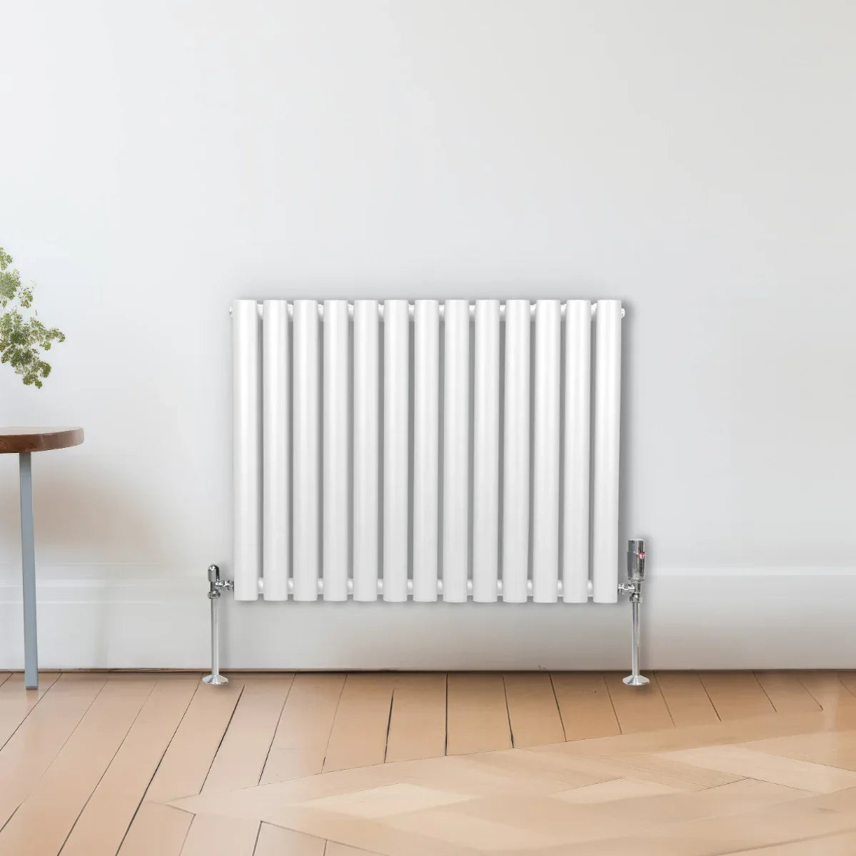 Sleek white oval column radiator with vertical fins, mounted on the wall, complementing a modern interior with wooden flooring