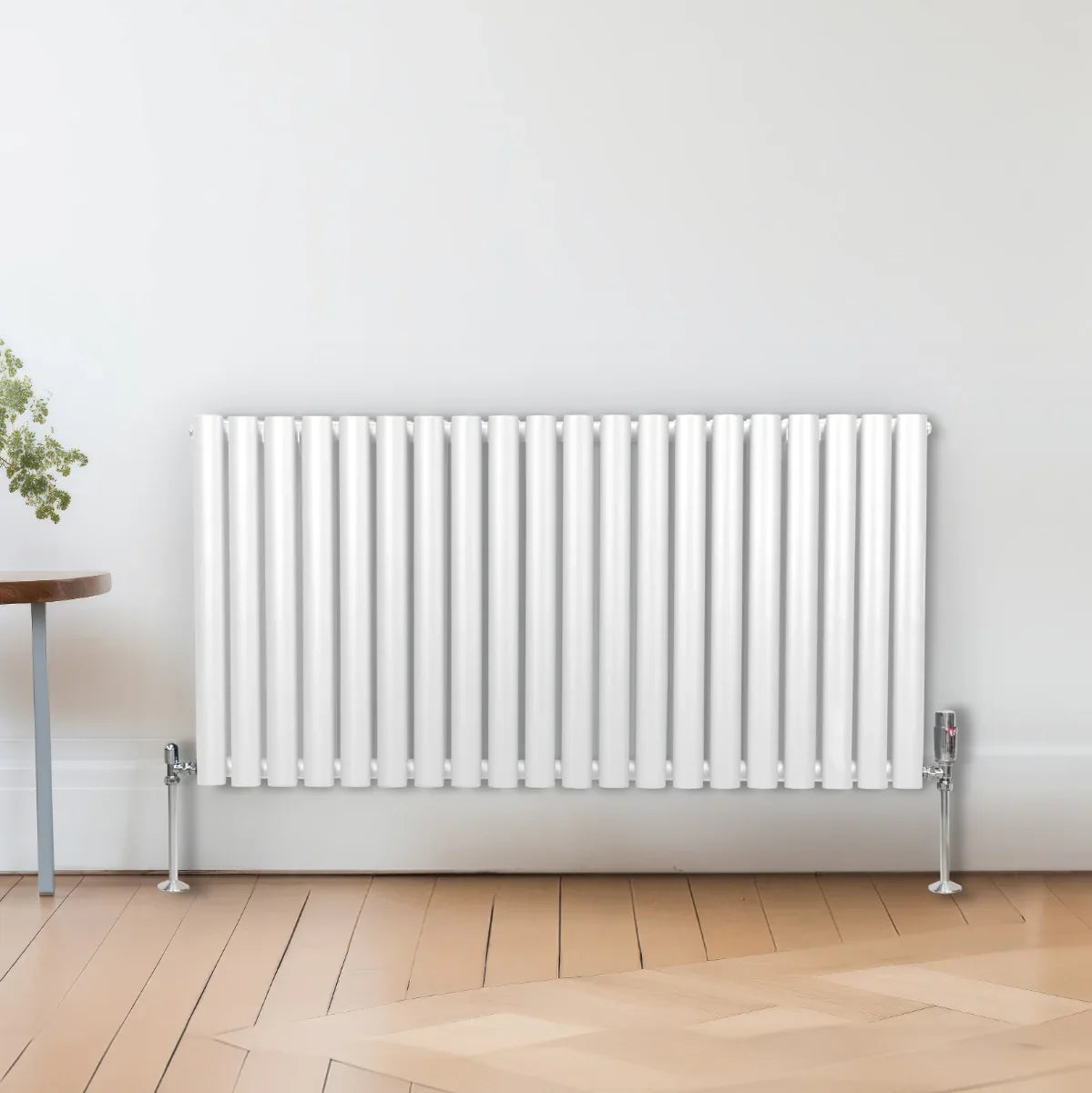 White oval column radiator, 600mm x 1200mm, featuring sleek vertical lines and chrome feet, set against a light wall and wooden floor
