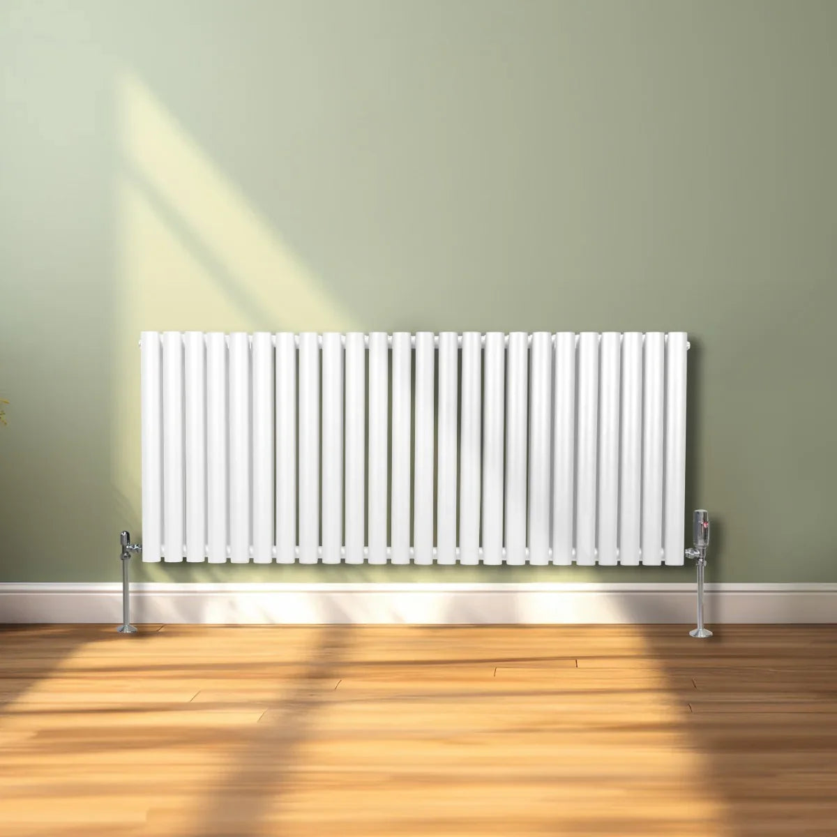 Sleek white oval column radiator, 600mm x 1440mm, mounted on a light wooden floor against a soft green wall, with sunlight casting shadows