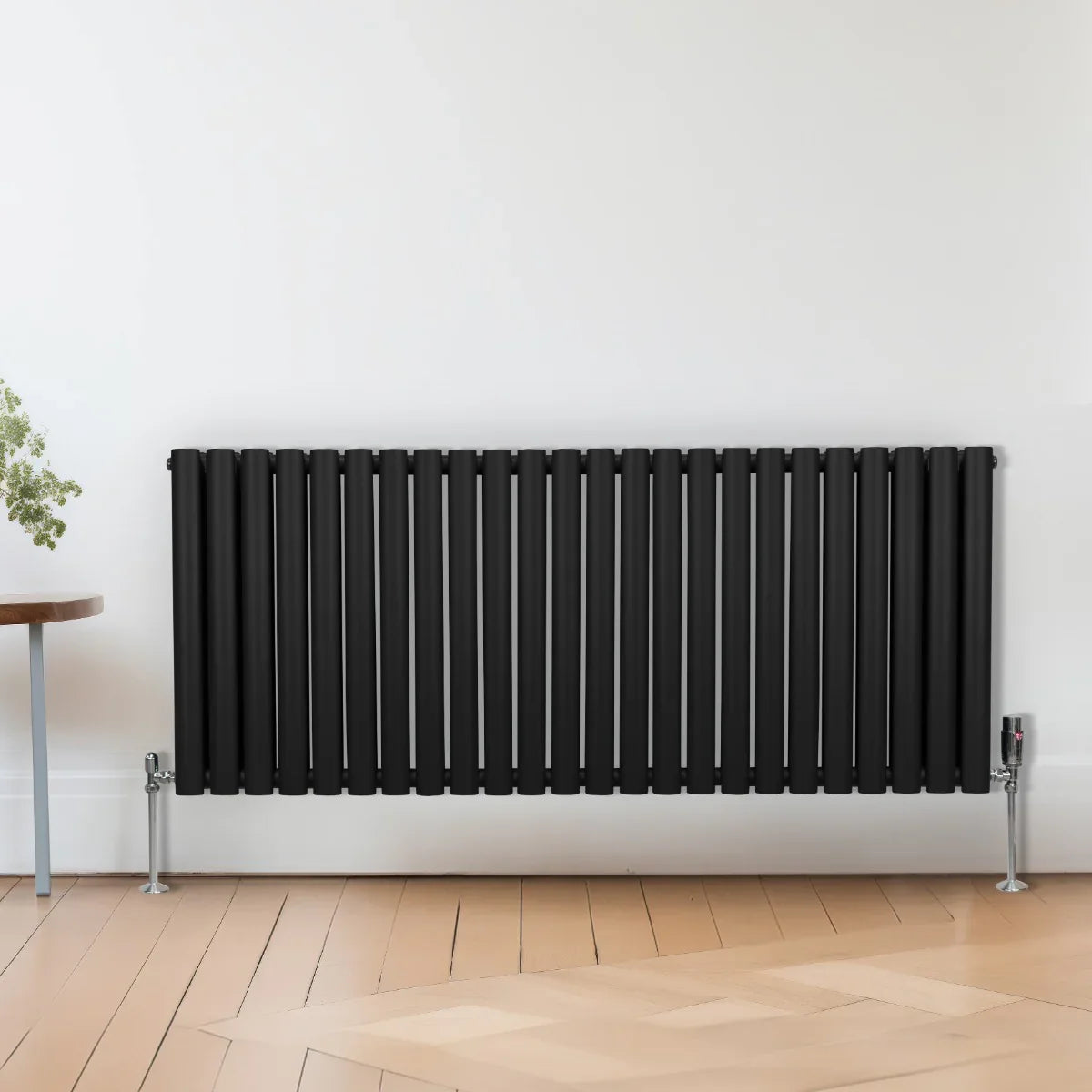 Sleek black oval column radiator, 600mm x 1440mm, featuring vertical slats and a modern design, mounted on stylish legs against a light wall
