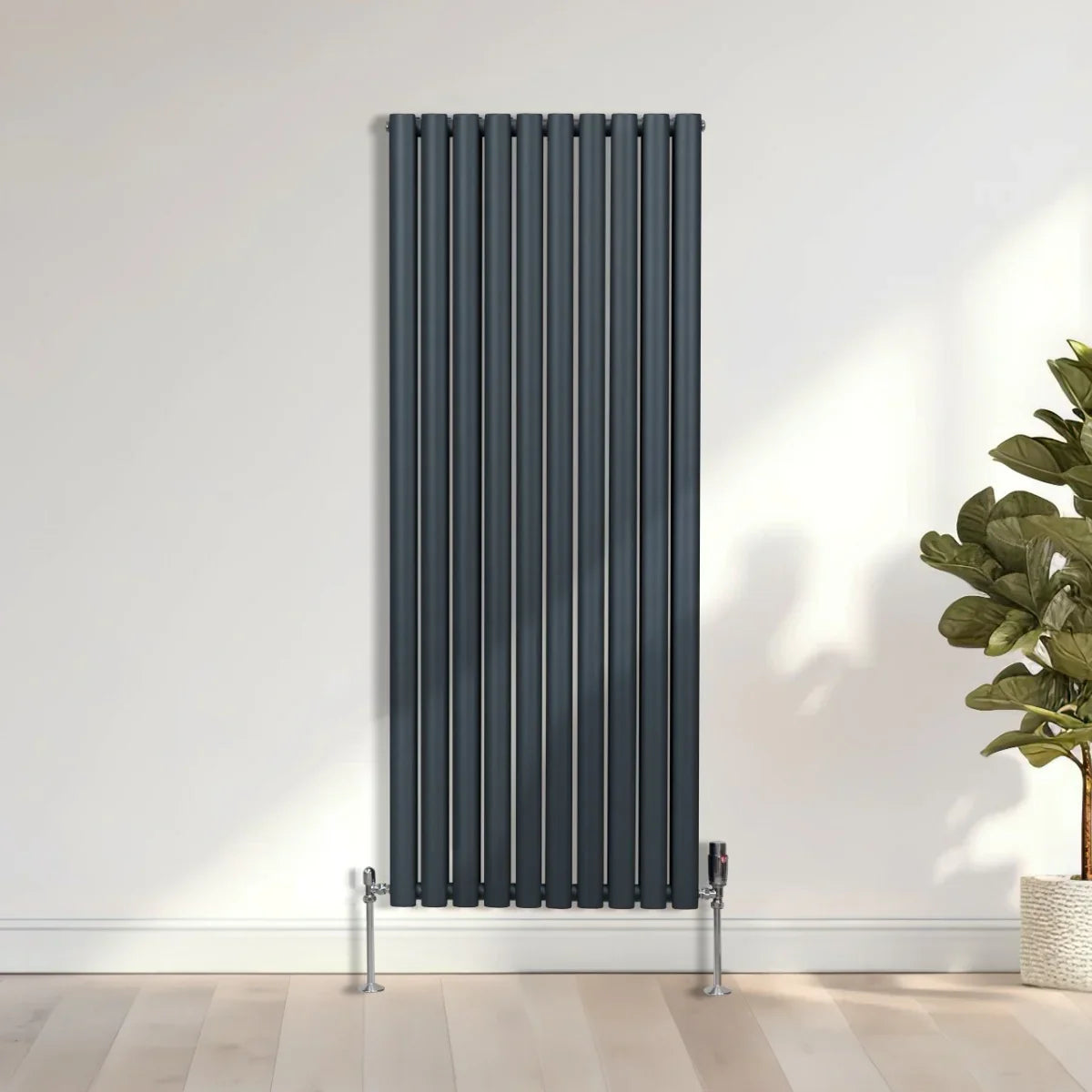 Oval column radiator in anthracite grey, featuring sleek vertical lines and a modern design, mounted on a light wooden floor