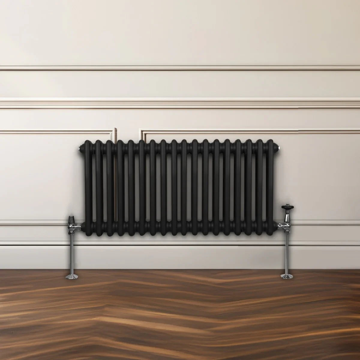 Traditional black 2 column radiator with a sleek design, featuring vertical tubes and chrome valve fittings, mounted on a wooden floor