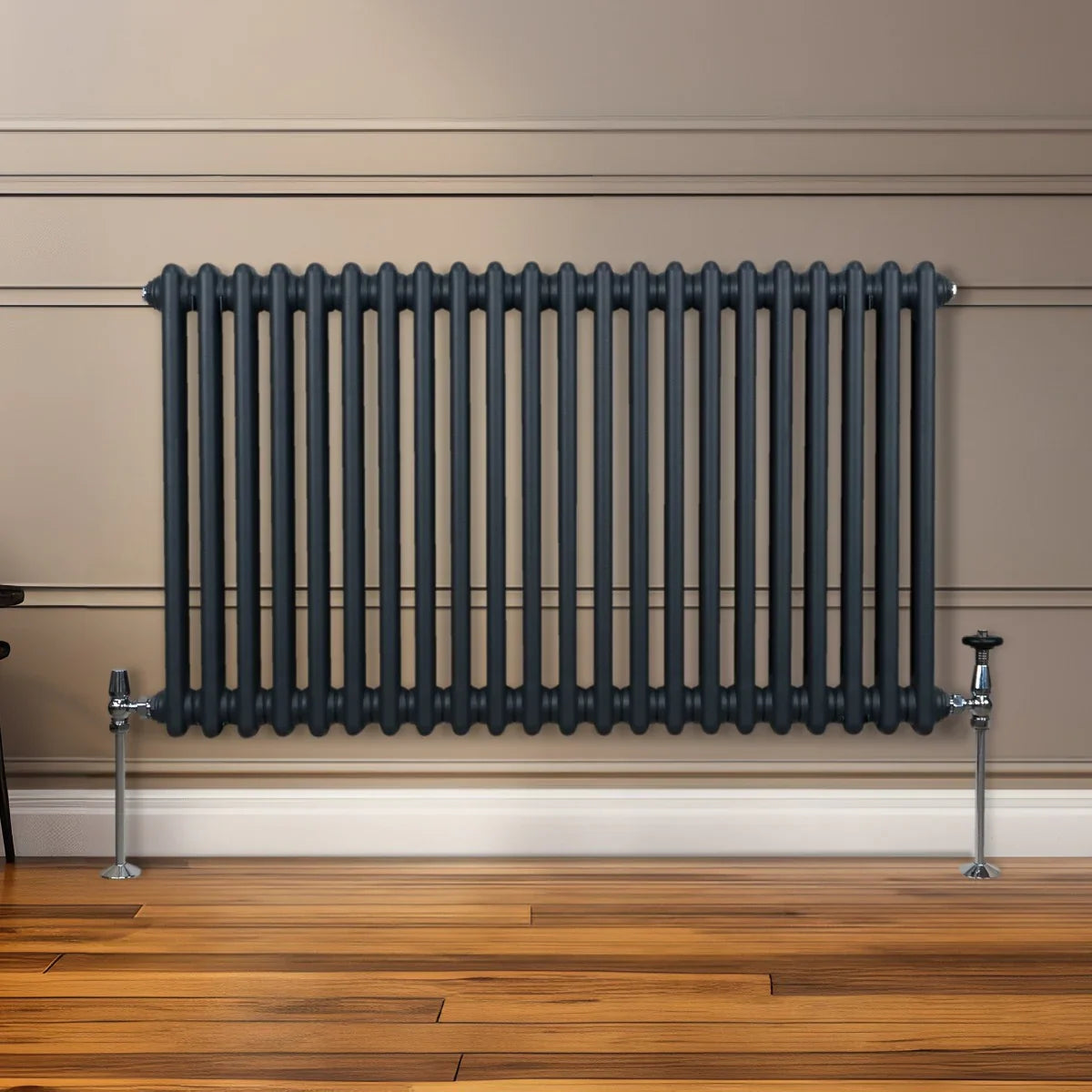 Traditional 2 column radiator in anthracite grey, featuring a sleek, ribbed design and mounted on a wooden floor against a wall