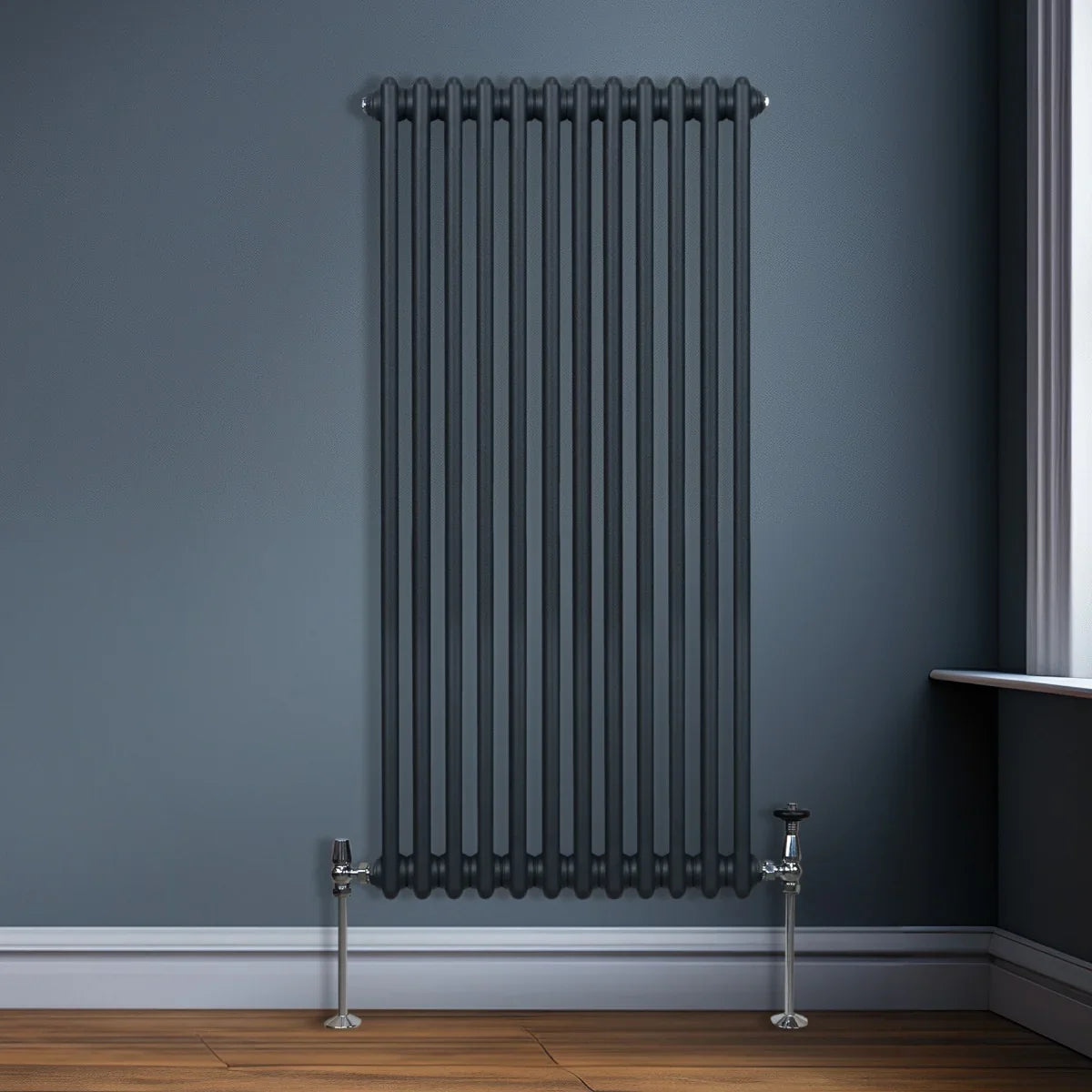 Traditional 2 column radiator in anthracite grey, featuring vertical tubes and sleek chrome valves, mounted on a wall with wooden flooring