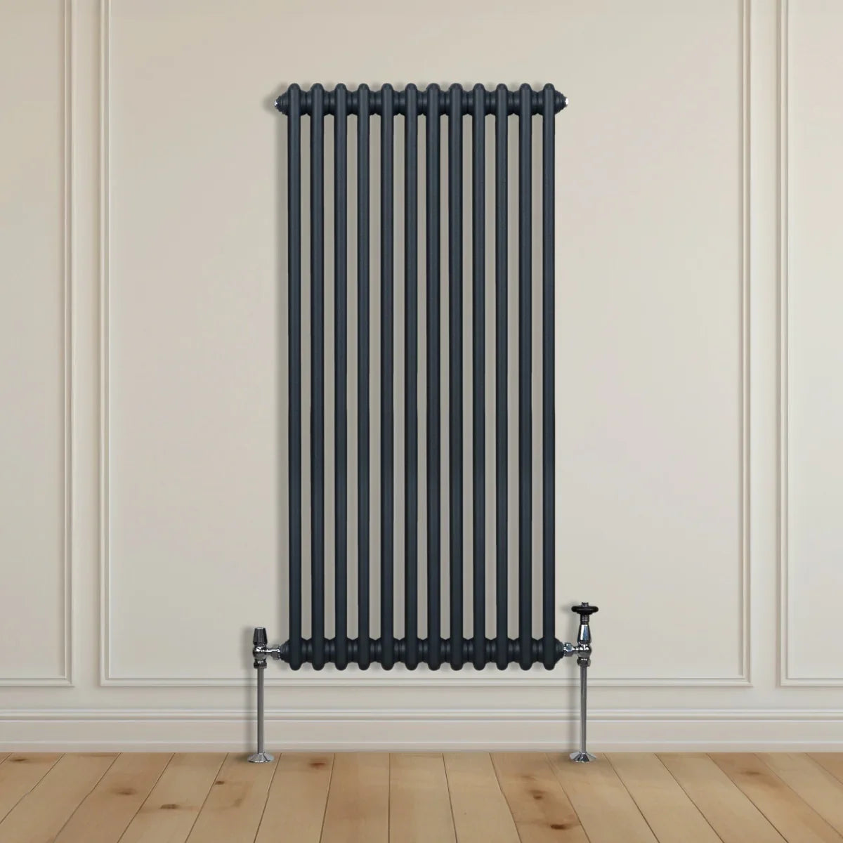 Traditional 2 column radiator in anthracite grey, featuring vertical bars and sleek metallic valves, set against a light wall and wooden floor