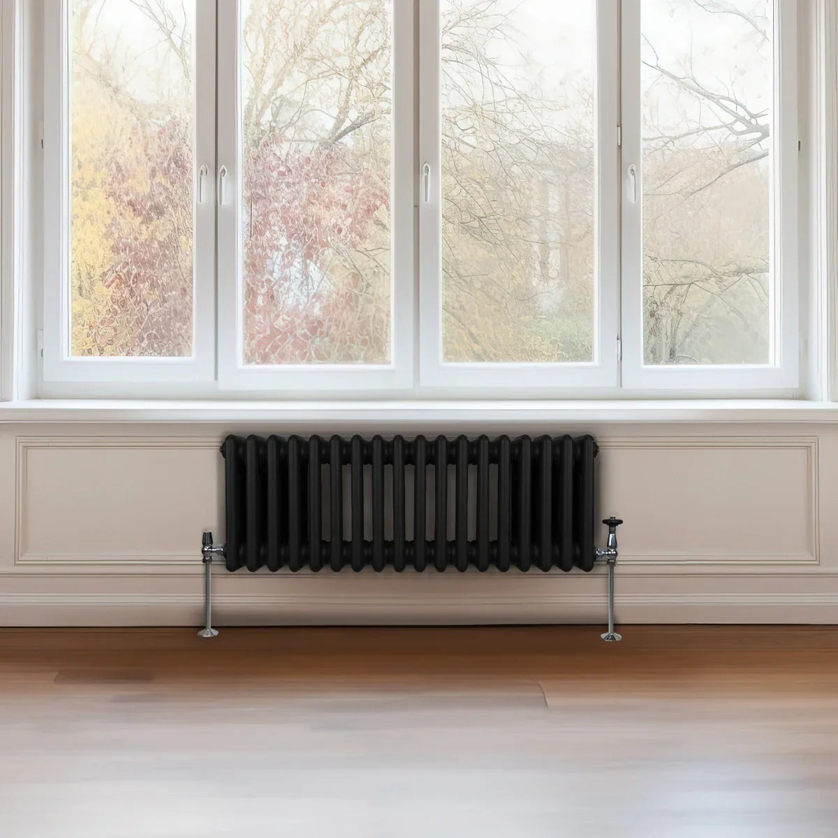 Traditional black 3 column radiator, 300 x 832mm, installed beneath large windows, complementing a modern interior with wooden flooring