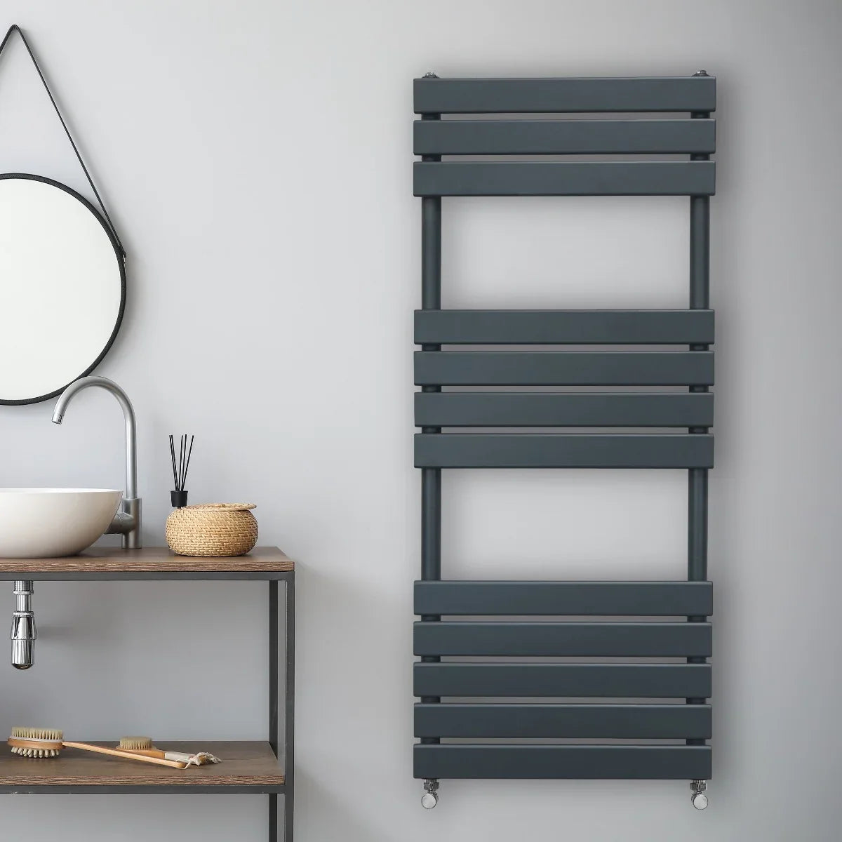 Flat panel towel radiator in anthracite grey, featuring a sleek, modern design with horizontal slats, mounted on a wall above a wooden shelf