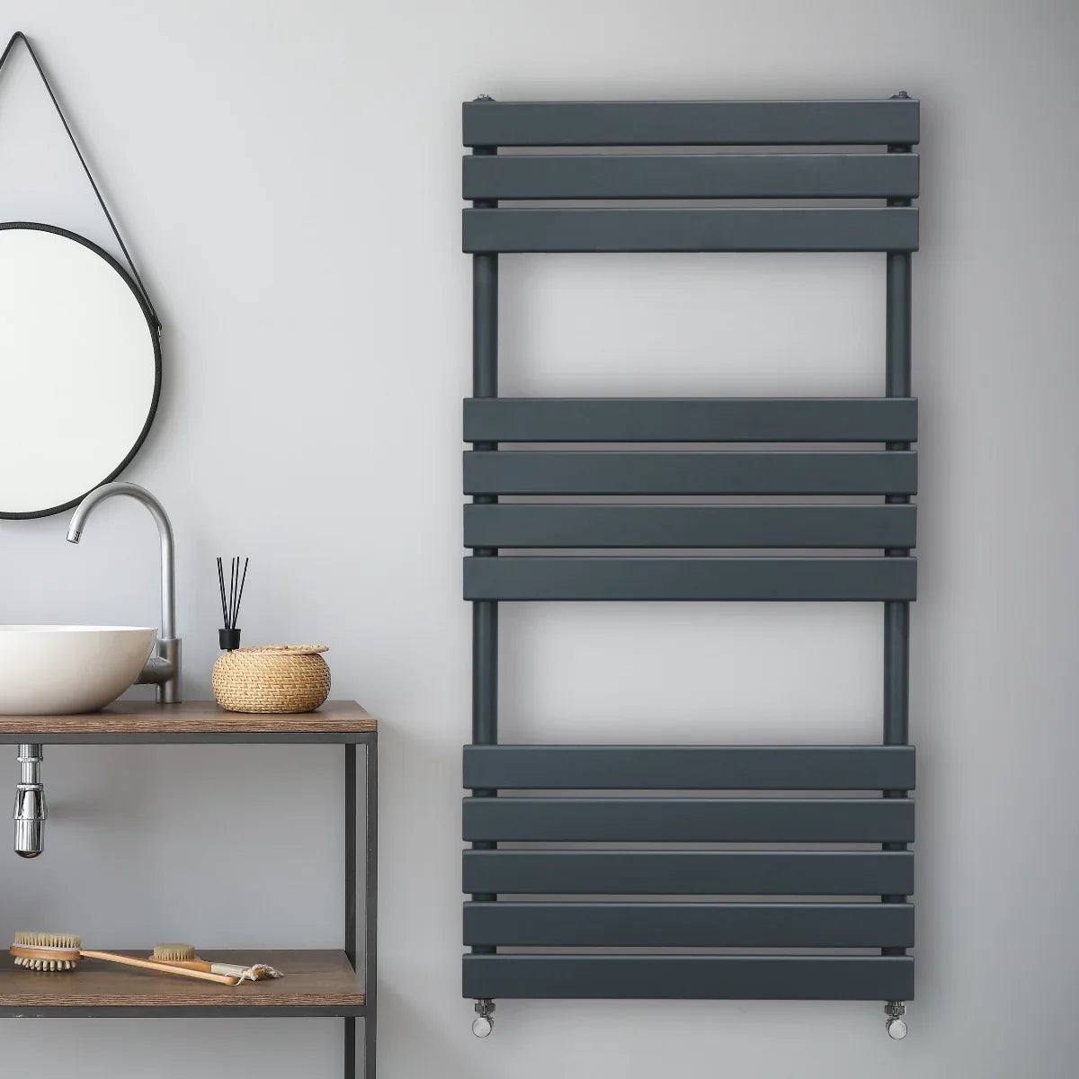 Flat panel towel radiator in anthracite grey, featuring sleek horizontal slats, mounted on a light grey wall above a wooden shelf