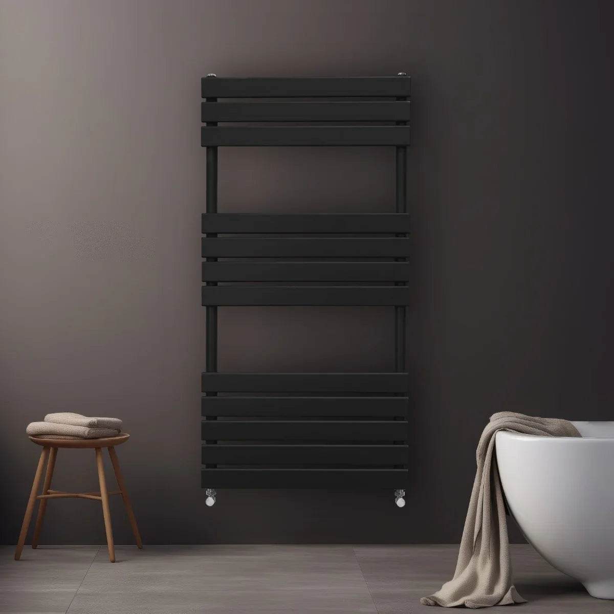 Sleek black flat panel towel radiator, 1200mm x 600mm, mounted on a dark wall, with a cozy towel draped over a wooden stool nearby