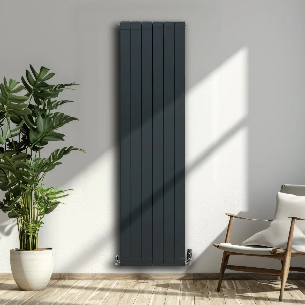 Slim anthracite grey aluminium radiator, 1800mm x 475mm, mounted on a wall with sunlight casting shadows, surrounded by indoor plants and a chair