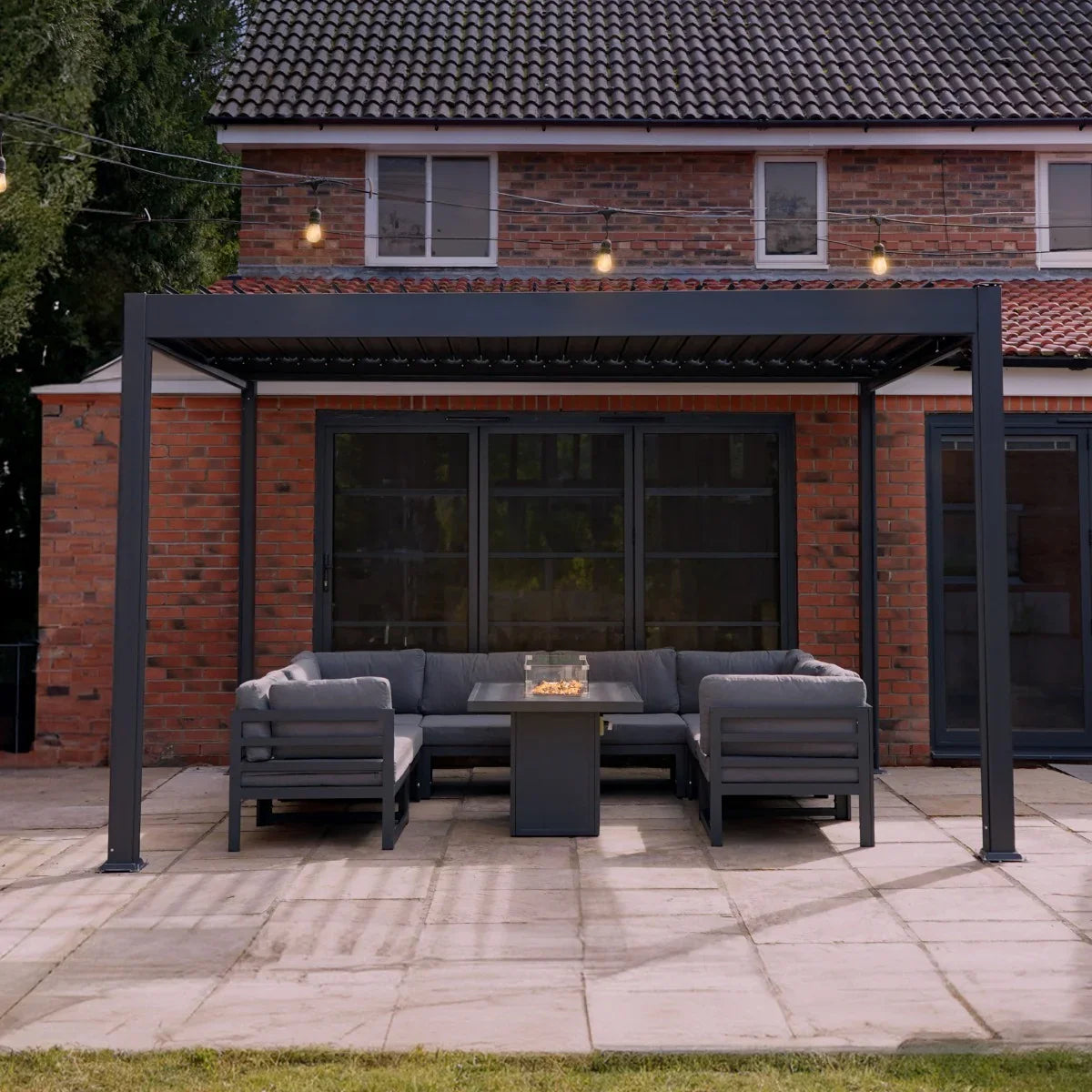 Anthracite aluminium pergola measuring 3m x 4m, featuring a sleek design, supporting a cozy outdoor seating area with a fire table
