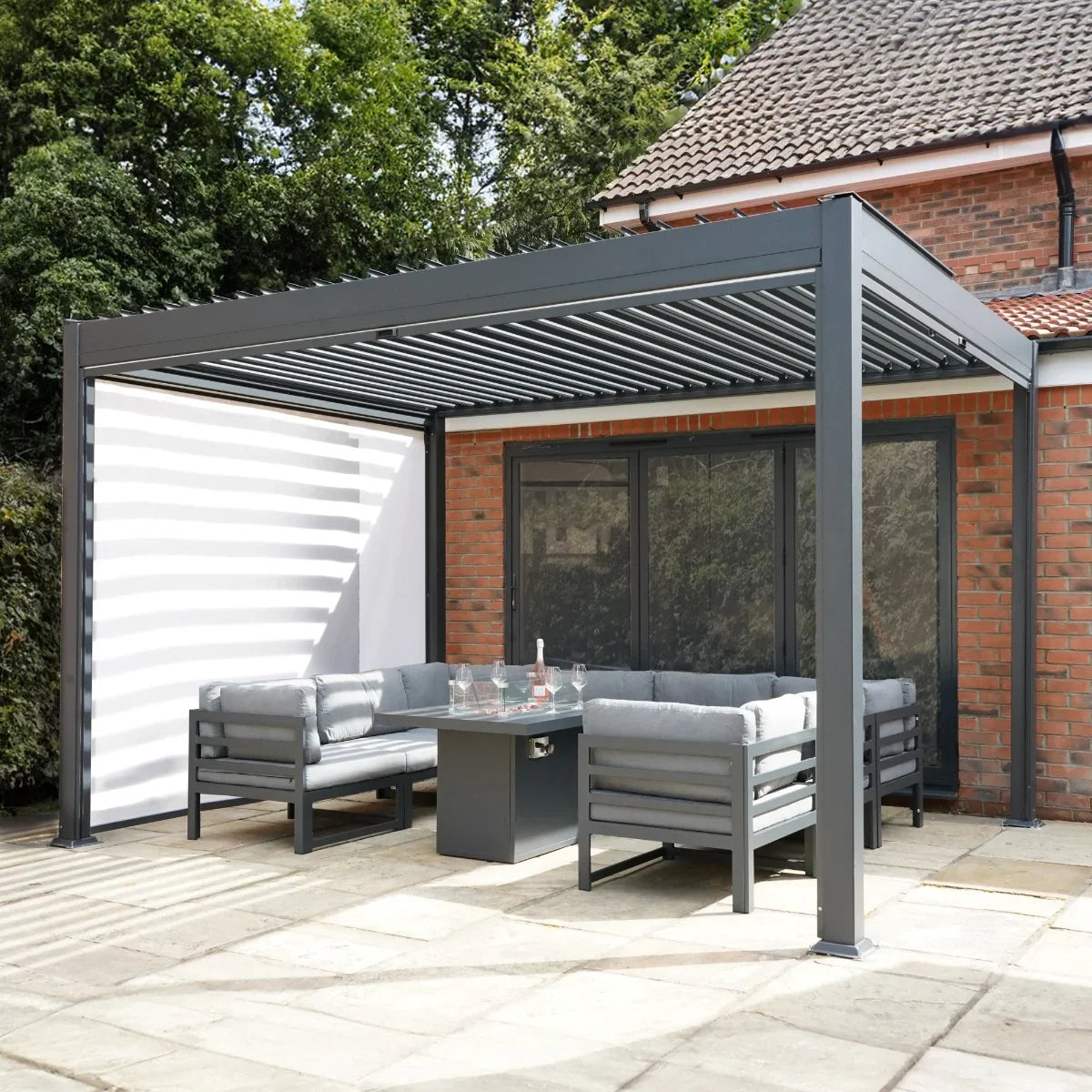 Anthracite aluminium pergola with white blinds and integrated LED lights, featuring a modern design and cozy seating area