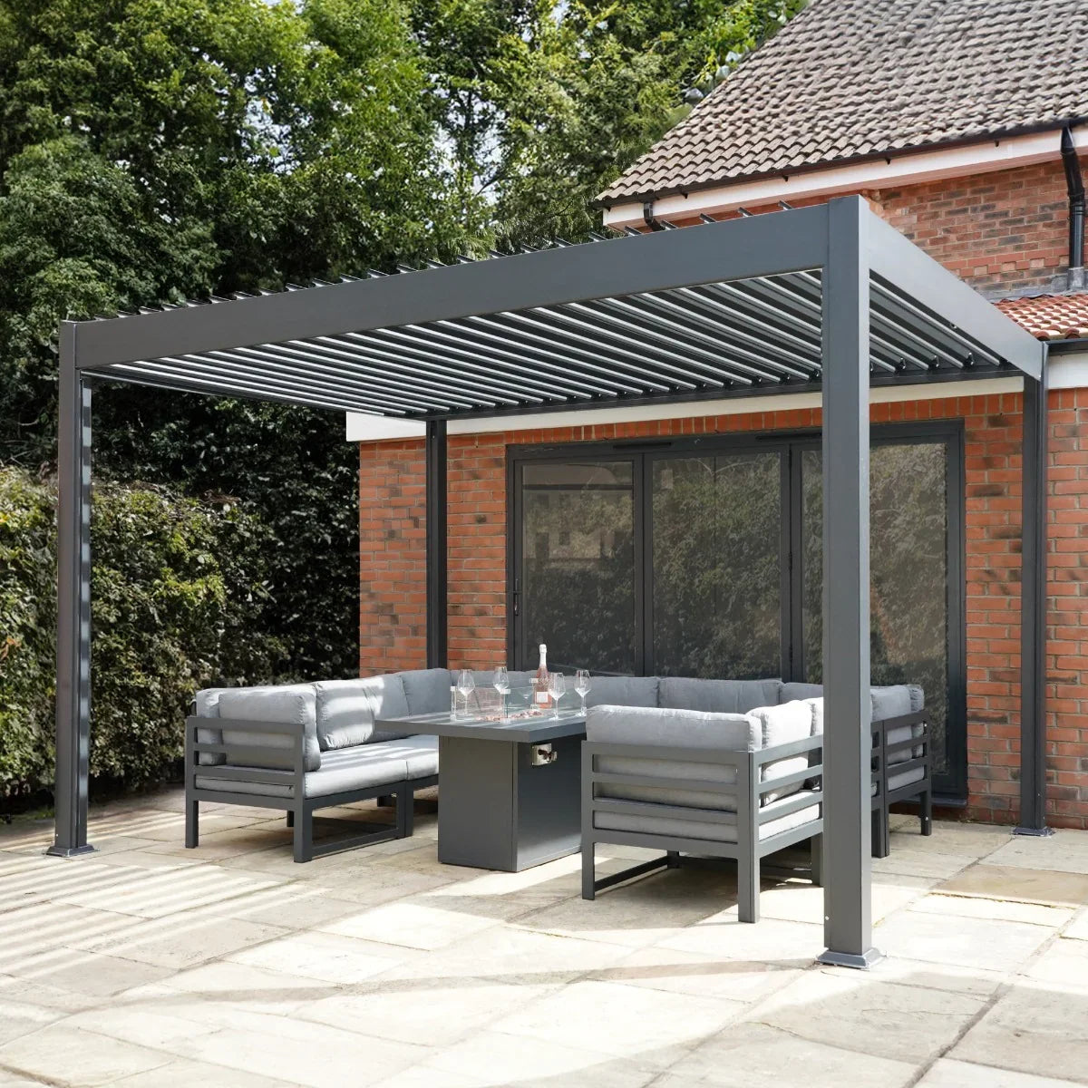 Anthracite aluminium pergola 3m x 3m with adjustable slats, enhancing a modern outdoor seating area with grey cushions and a glass table
