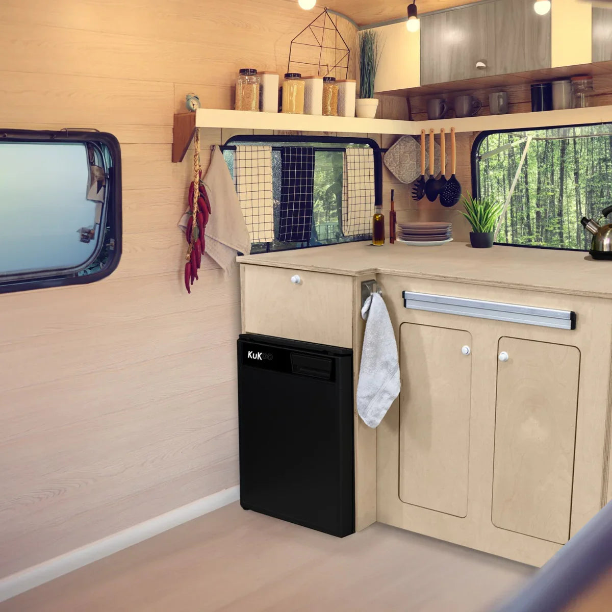 Compact camper kitchen pod featuring a sleek black compressor fridge, wooden cabinetry, and organized cooking utensils in a cozy interior setting
