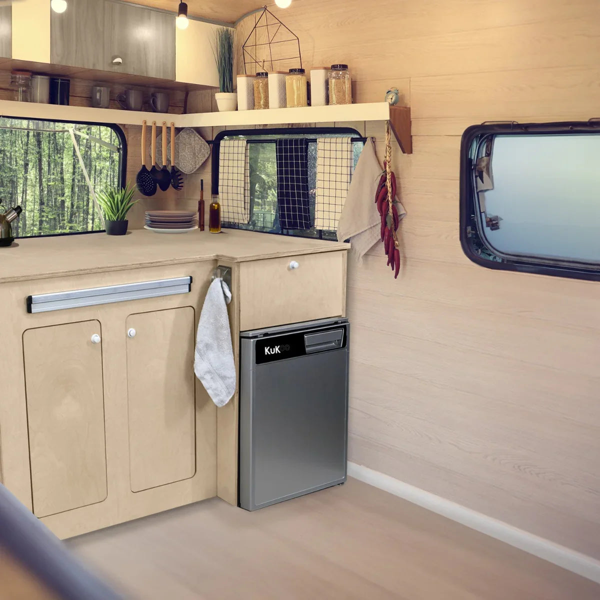 Camper kitchen pod featuring sleek silver compressor fridge, wooden cabinetry, and modern decor in a cozy, well-lit interior