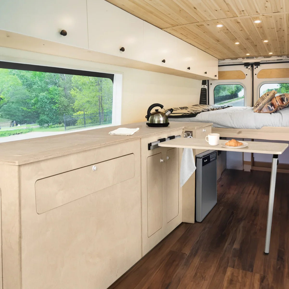 Camper Kitchen Pod with sleek beige cabinetry, silver compressor fridge, and a cozy interior featuring wood accents and natural light
