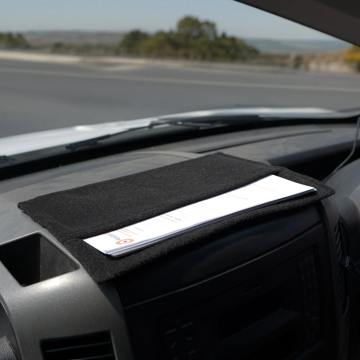 Black van carpet lining with storage pouches, featuring a soft texture, designed to fit on a dashboard for organized storage