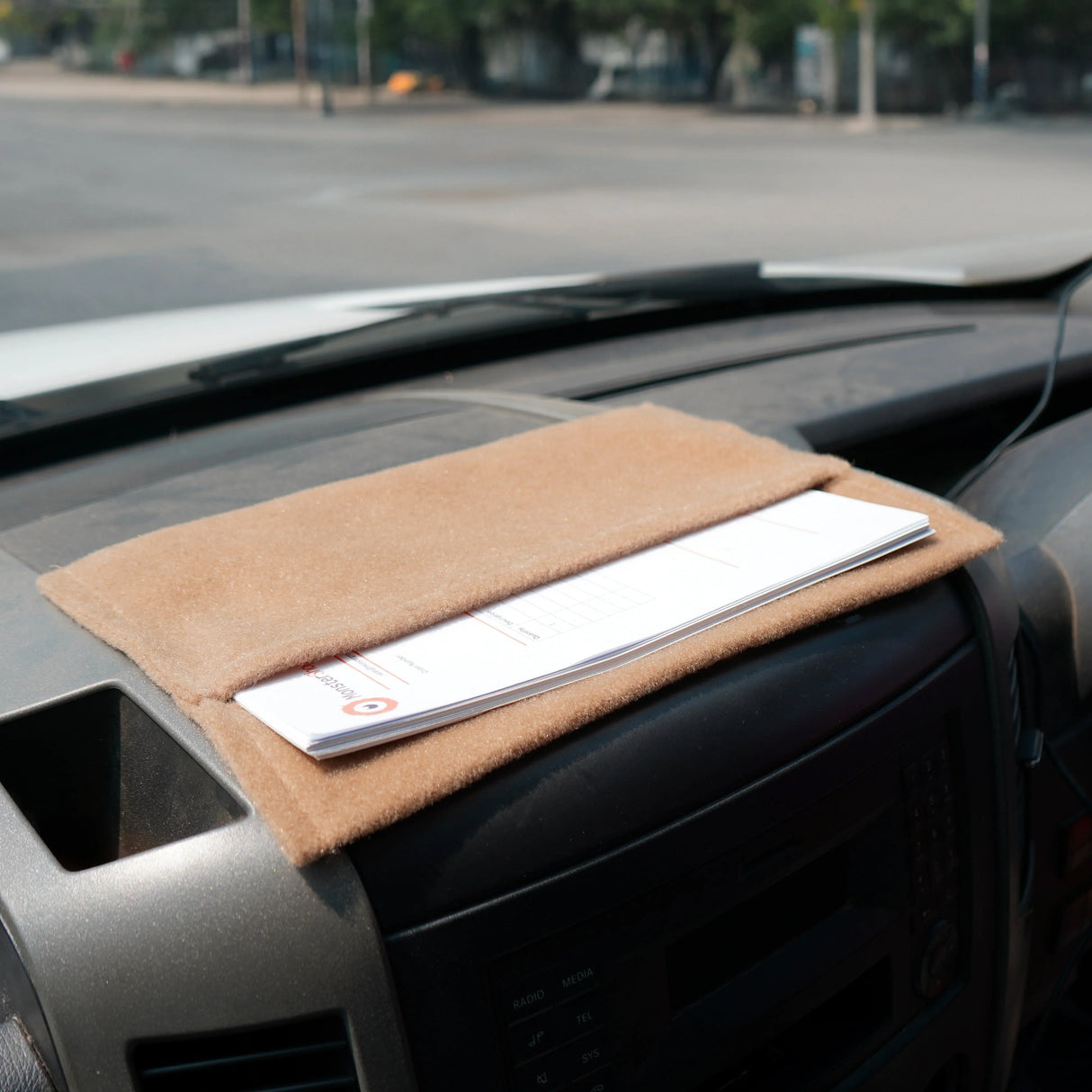 Beige van carpet lining on dashboard, featuring a soft texture, designed for storage pouches and organization in vehicles